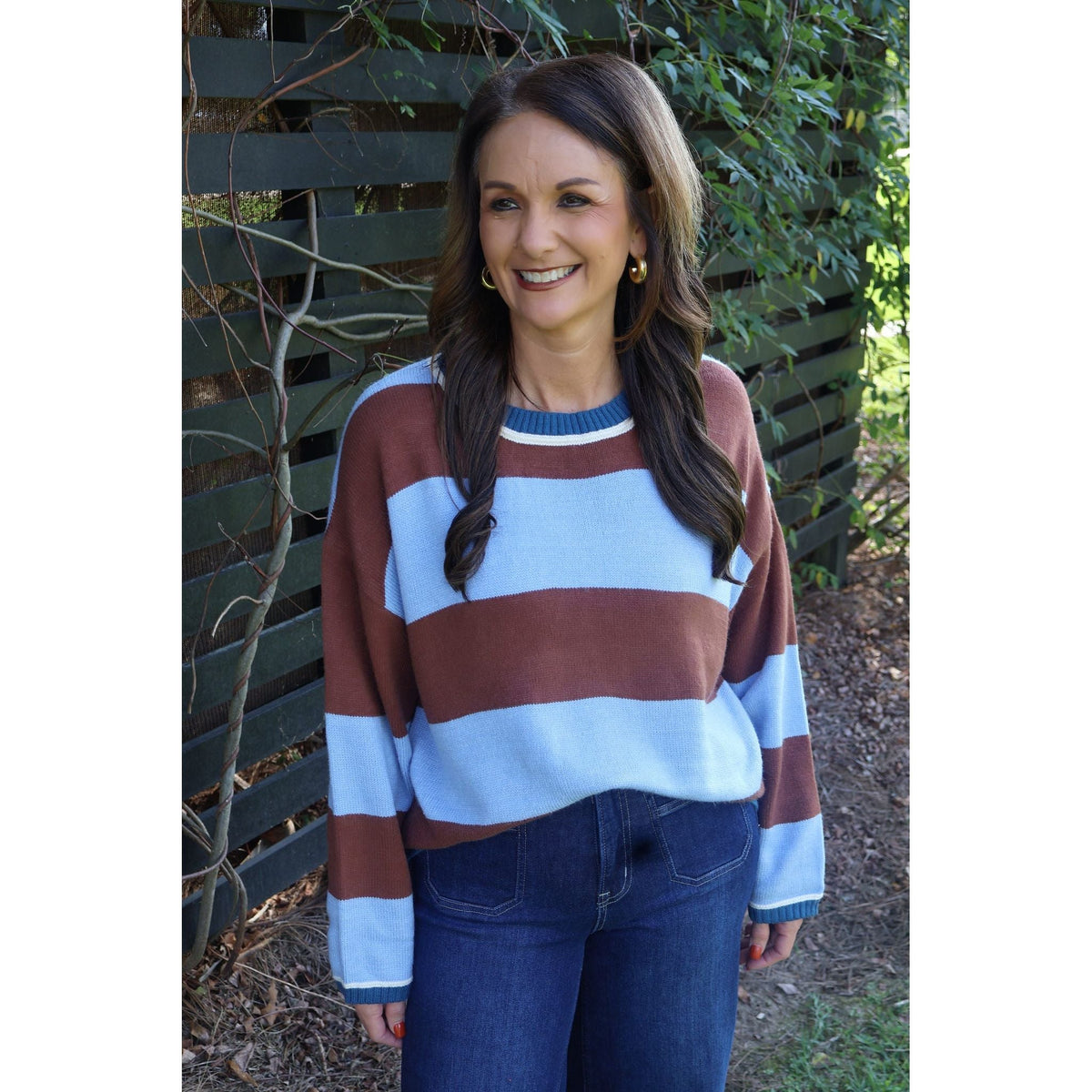 Annie Ks Boutique blue and brown wide stripe crew neck sweater worn by a smiling woman with dark hair outdoors