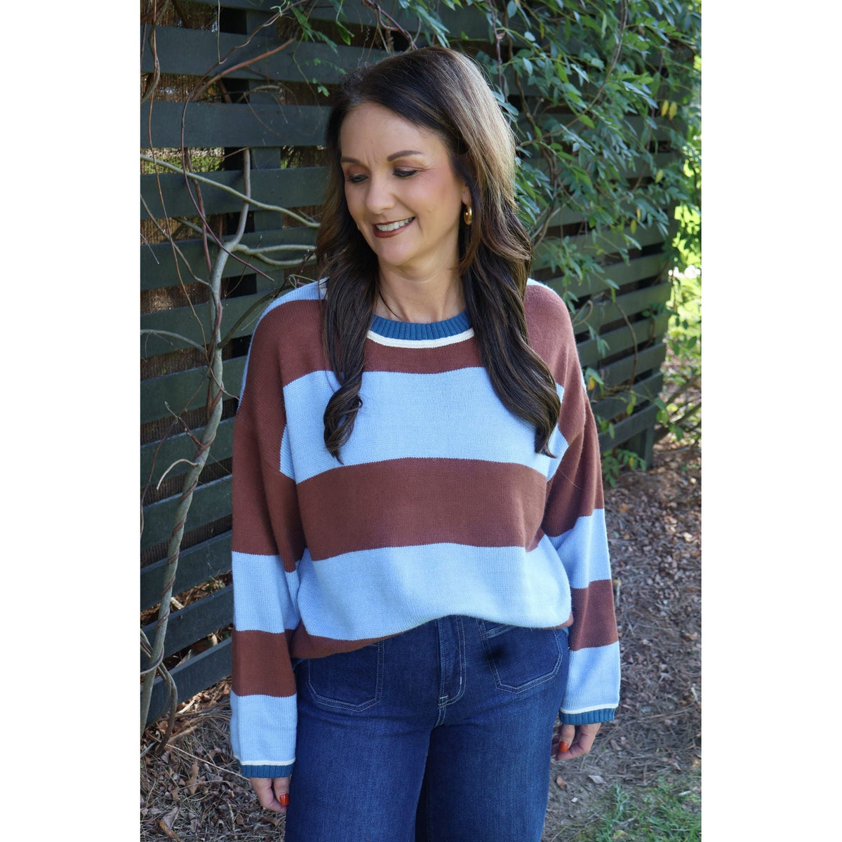 Annie Ks Boutique blue and brown wide stripe crew neck sweater worn by a woman with dark hair in a garden setting