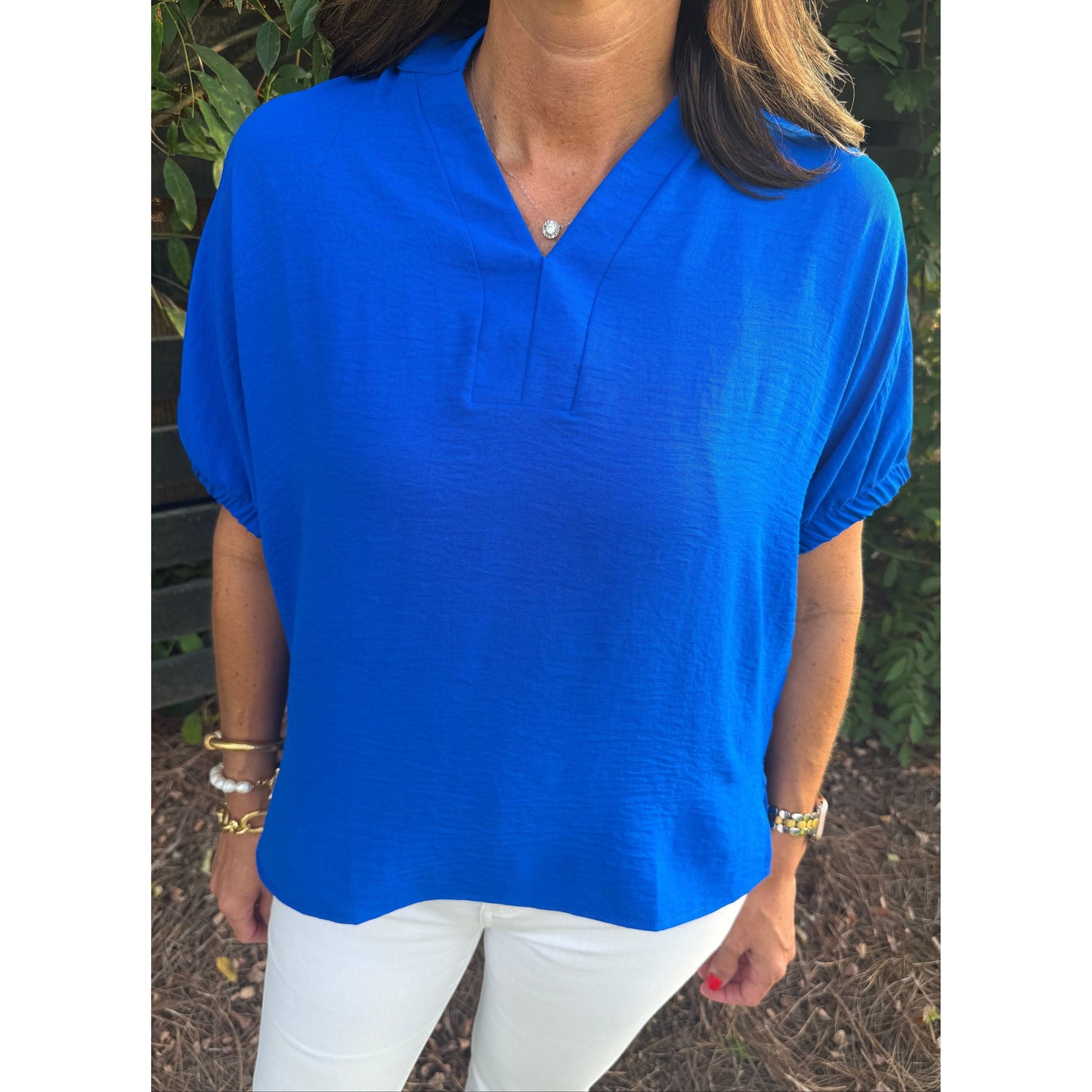 Annie Ks Boutique blue split neck dolman top with elastic elbow cuffs worn with white pants
