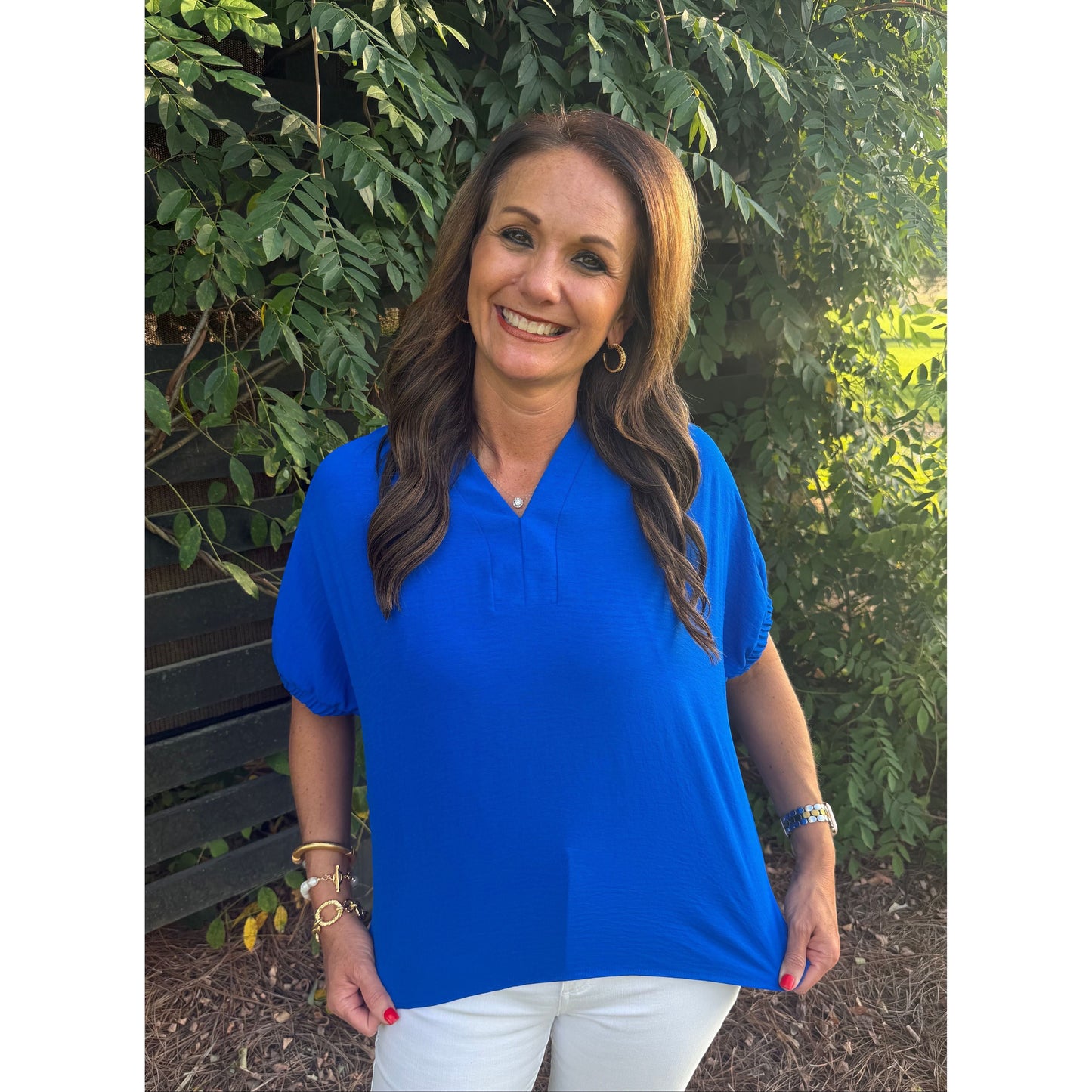Annie Ks Boutique blue split neck dolman top with elbow-length sleeves worn by a smiling woman outdoors