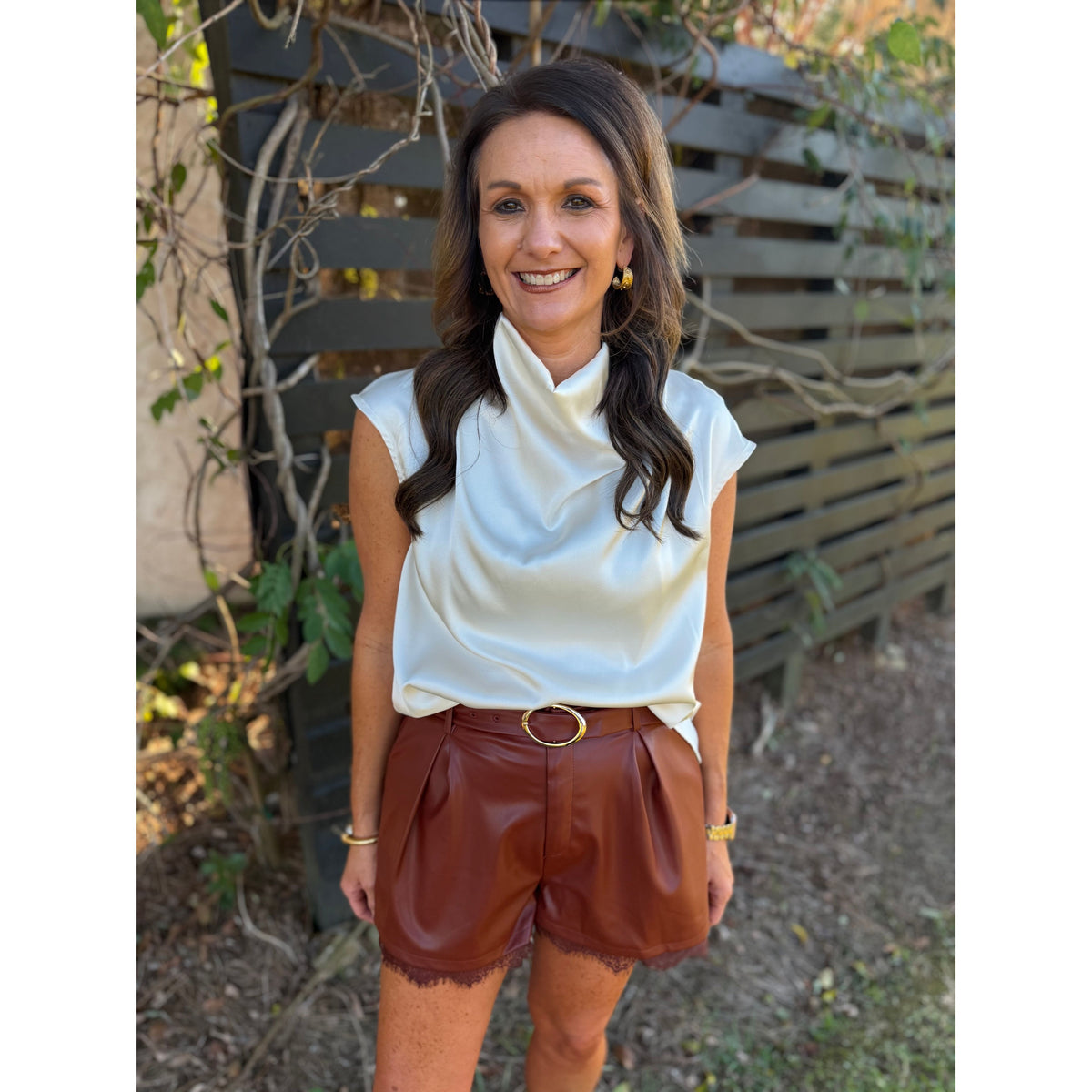 Annie Ks Boutique brick faux leather pleated shorts featuring a delicate lace hem and matching belt with gold buckle.