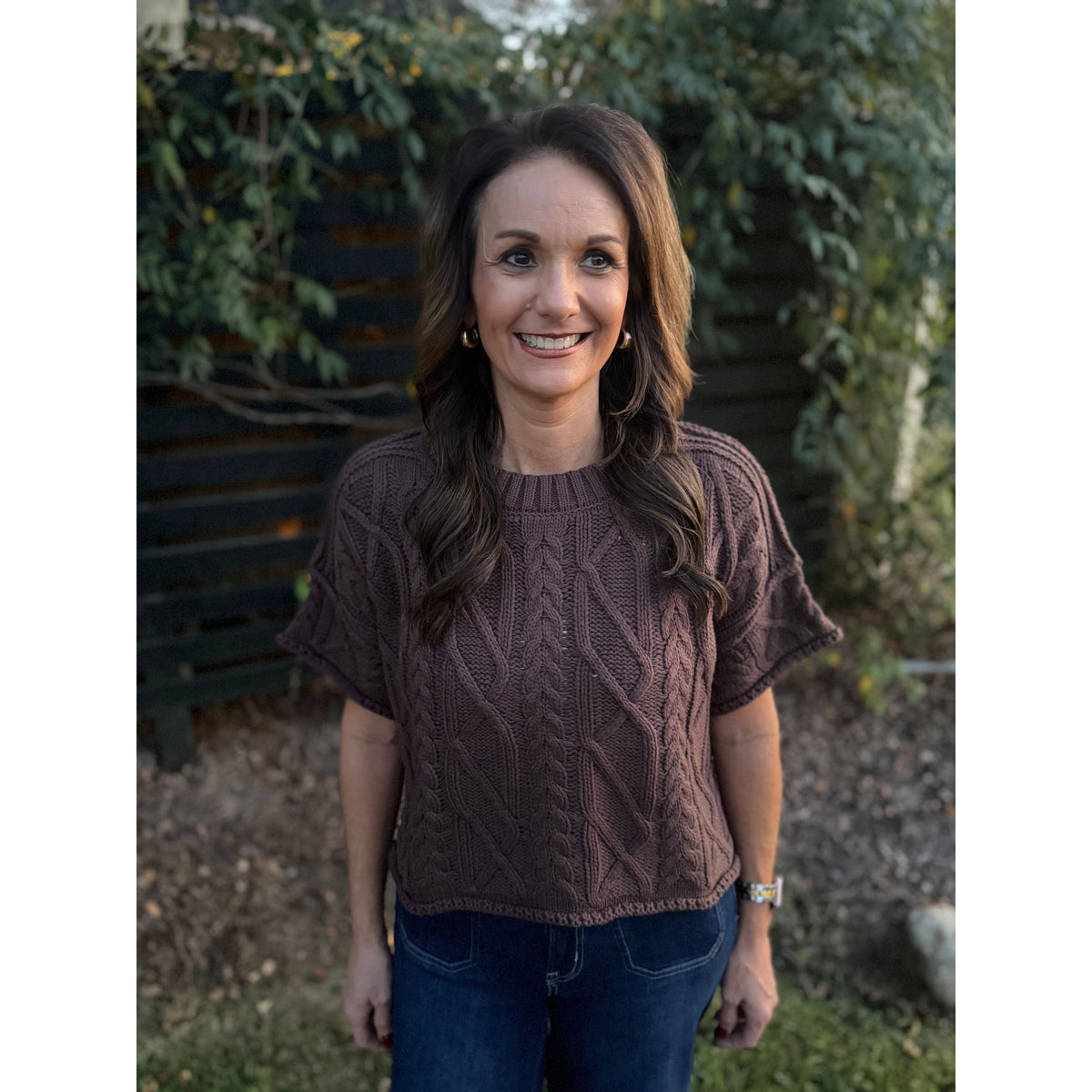 Annie Ks Boutique brown short sleeve cable knit sweater with a round neck and cropped boxy fit worn by a woman