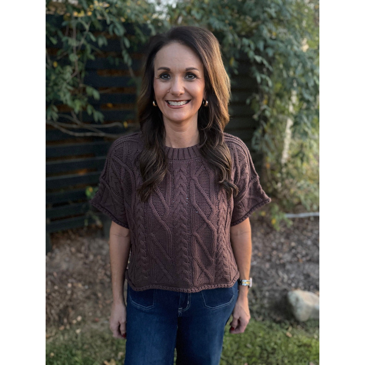 Annie Ks Boutique brown short sleeve cable knit sweater with a round neck and cropped boxy fit worn by a woman