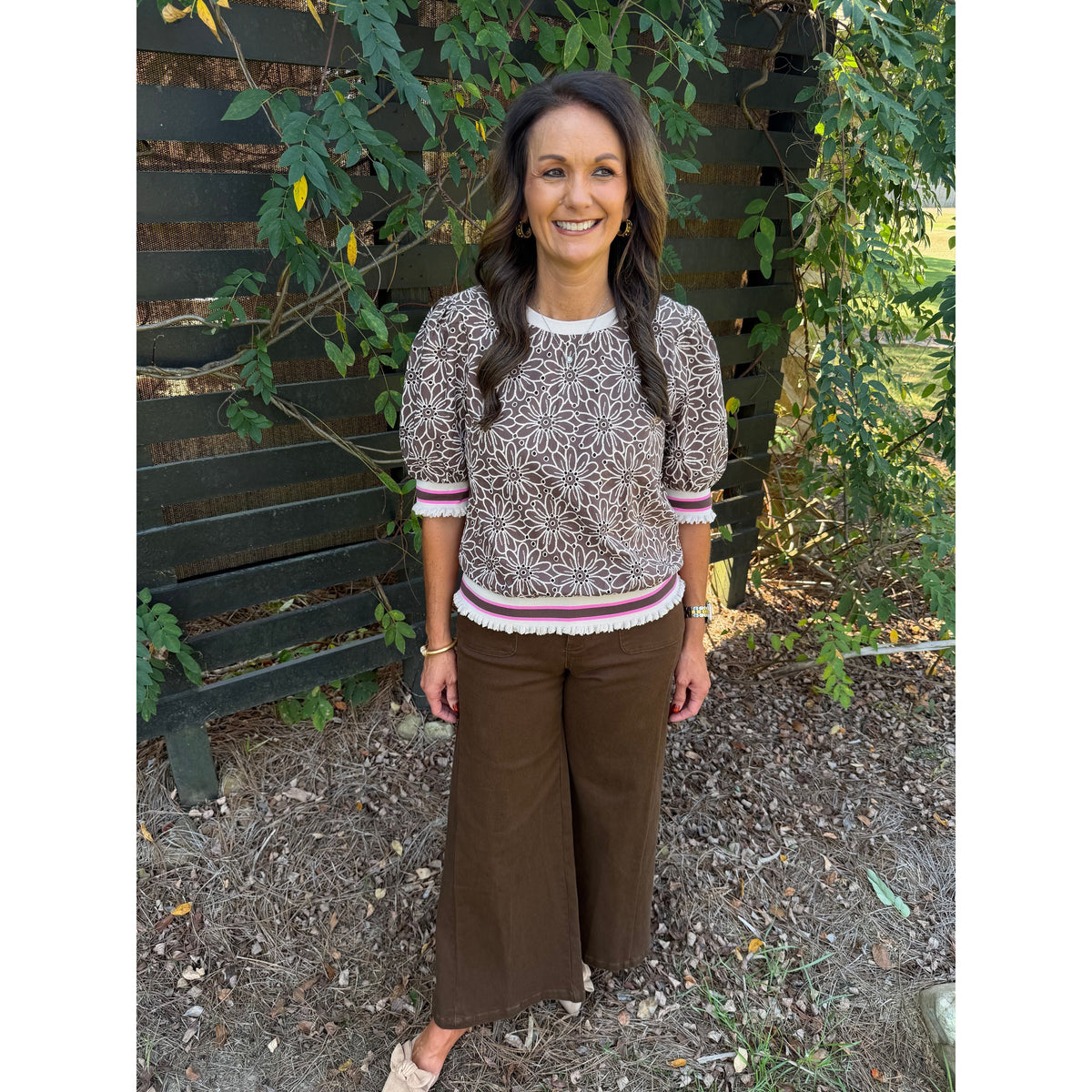 Annie Ks Boutique brown floral eyelet short sleeve top with puff sleeves and striped ribbed trim on a smiling model