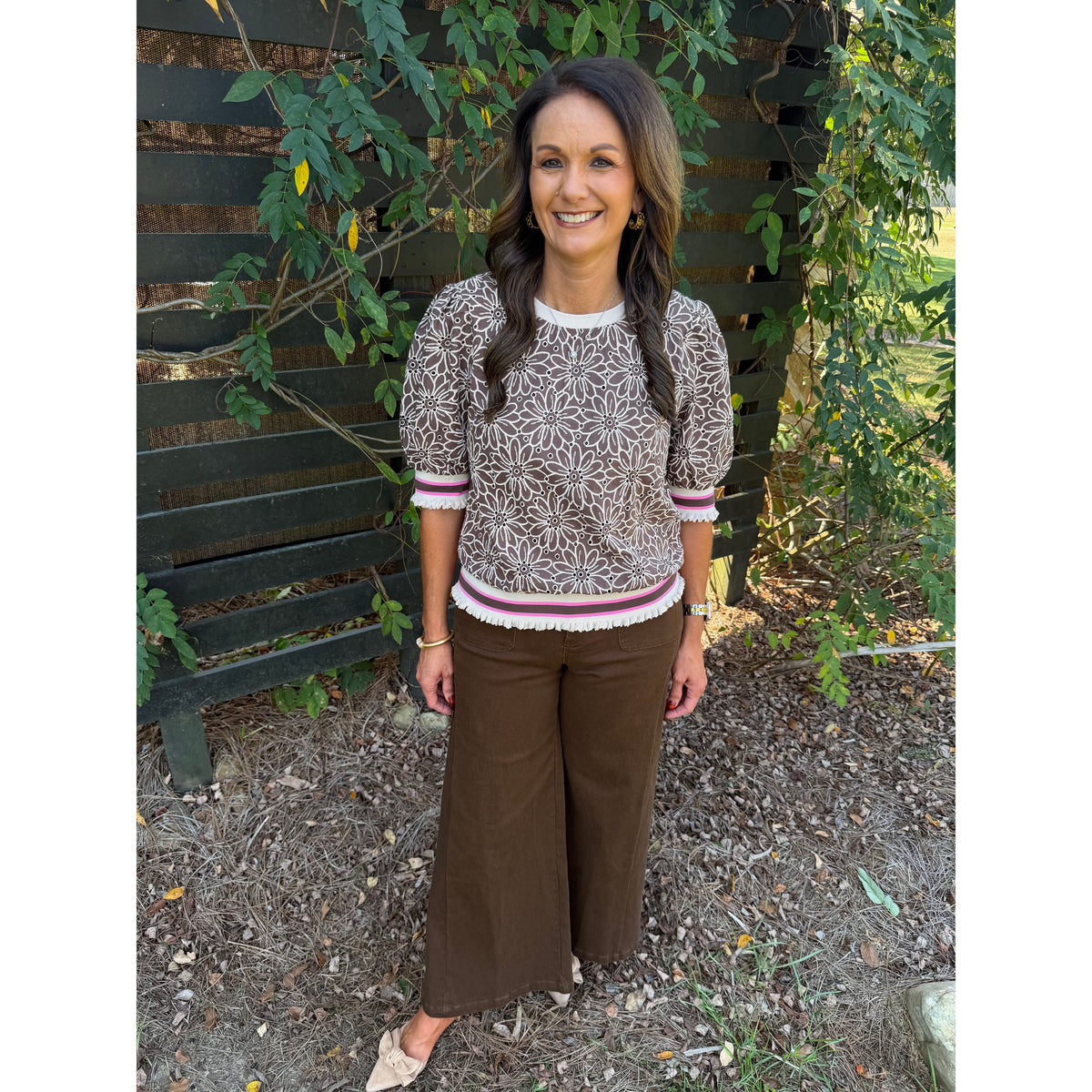 Annie Ks Boutique brown floral eyelet short sleeve top with puff sleeves and striped ribbed trim on a smiling model.