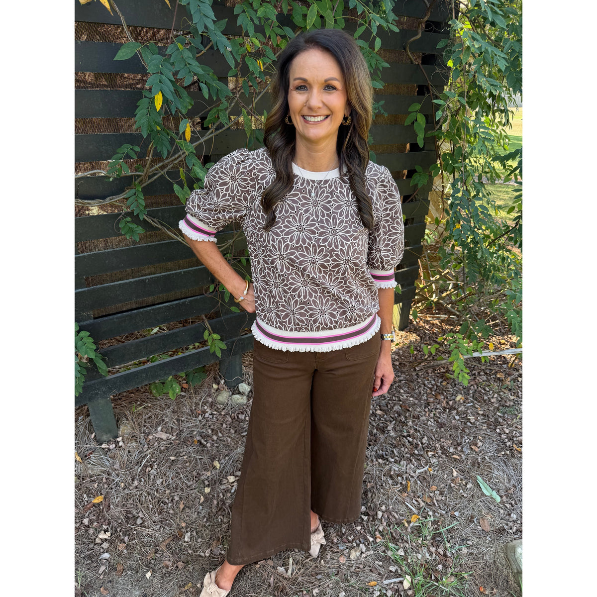 Annie Ks Boutique brown floral eyelet top with puff sleeves and striped ribbed trim worn by a smiling woman outdoors