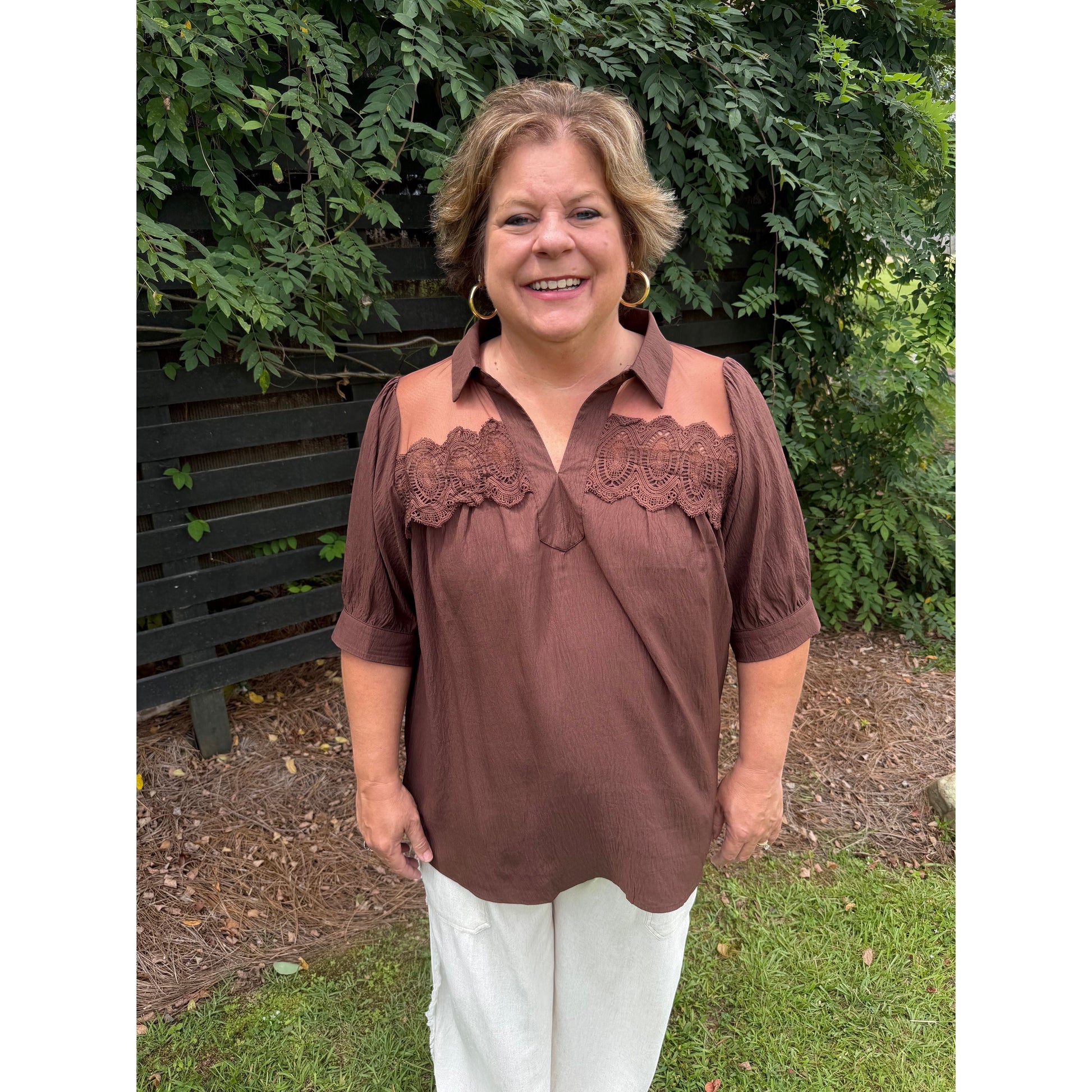 Annie Ks Boutique brown blouse with lace trim, collared neckline, and puff sleeves worn by a smiling woman outdoors.