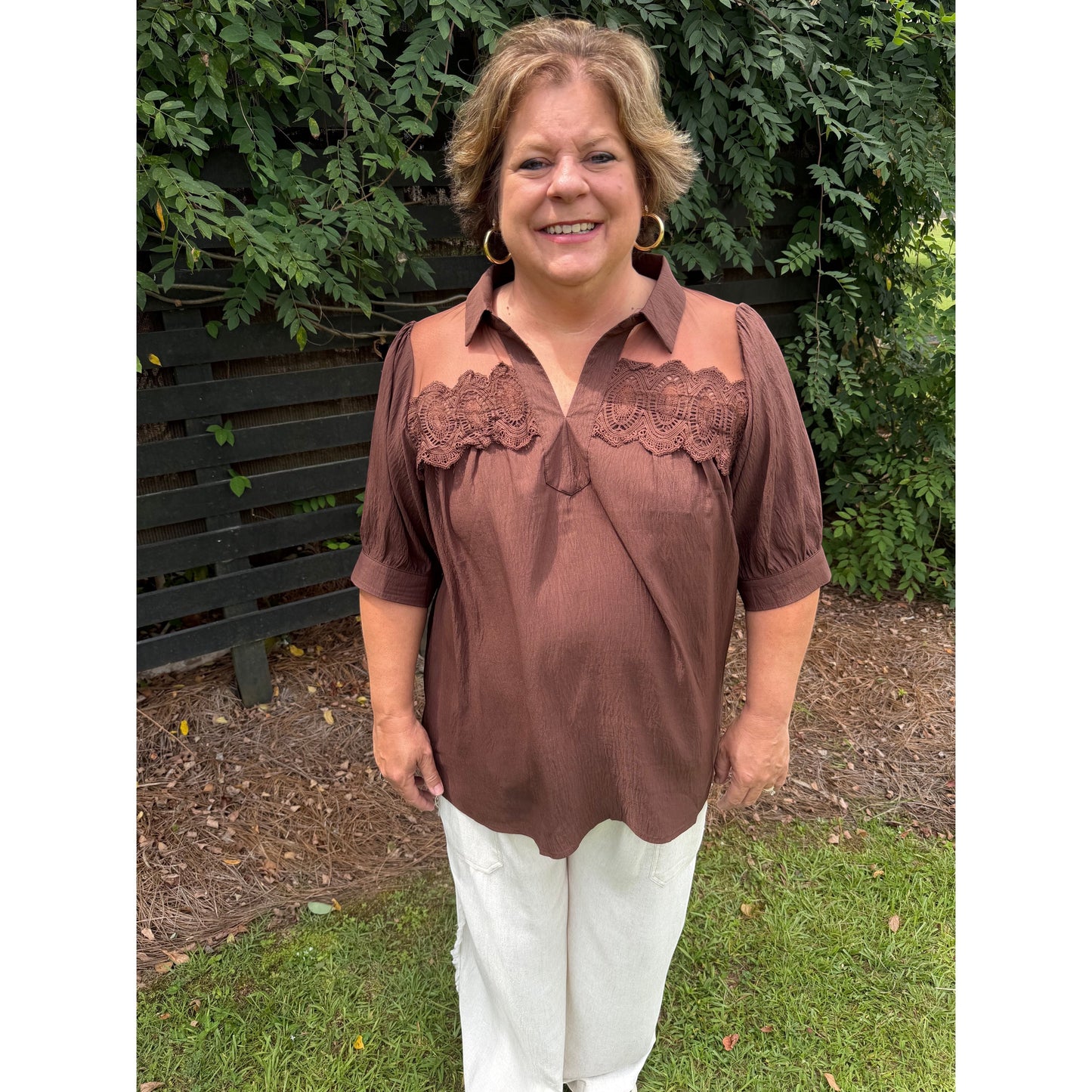 Annie Ks Boutique brown blouse with lace trim, sheer mesh shoulders, and puff sleeves worn with white trousers.