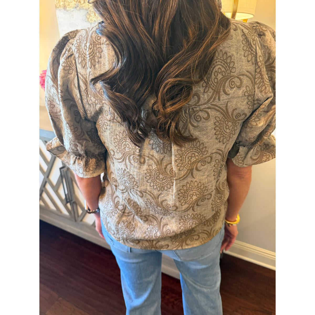 Annie Ks Boutique brown paisley print blouse with puff sleeves worn with light wash jeans, back view