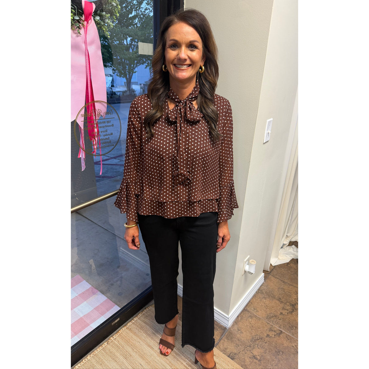 Annie Ks Boutique brown polka-dot blouse with bell sleeves and a neck bow tie worn with black trousers