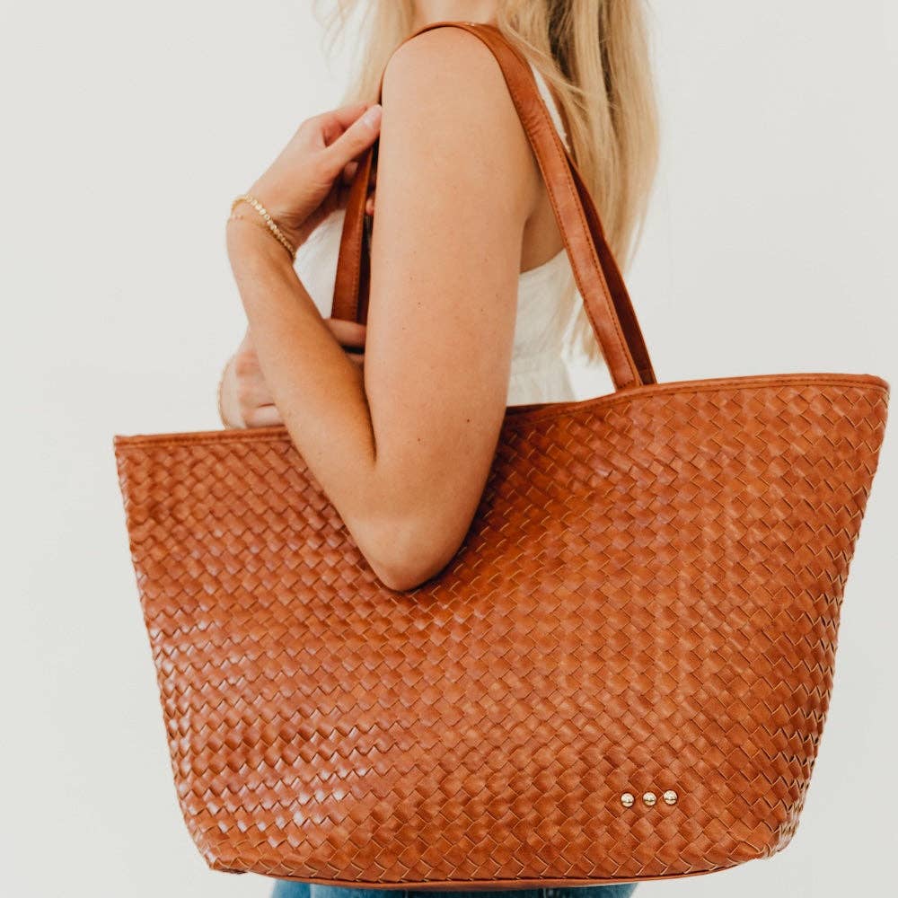 Annie Ks Boutique brown woven vegan leather tote bag with shoulder strap worn by a woman