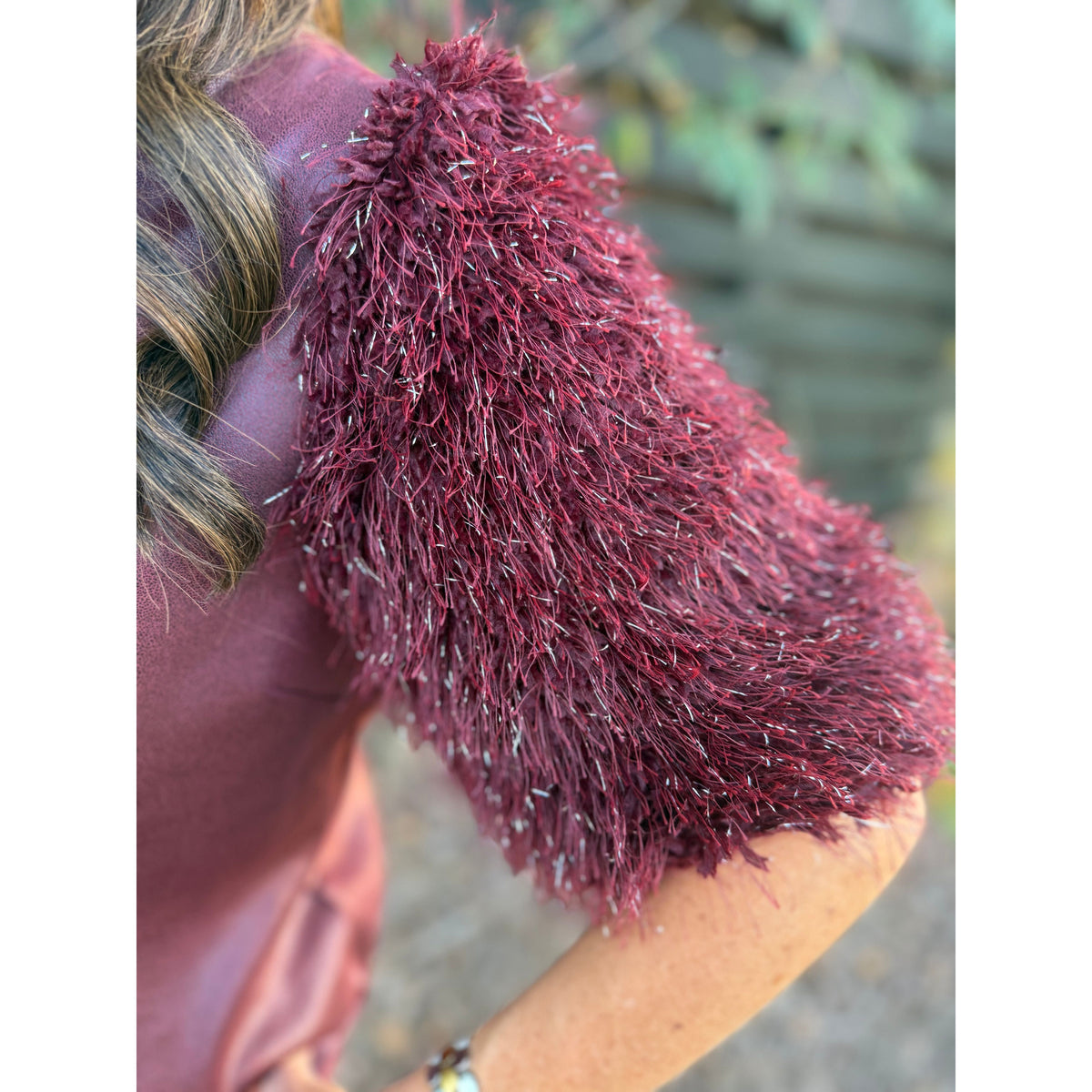 Annie Ks Boutique burgundy faux leather top featuring dramatic short sleeves with shimmering metallic feather fringe