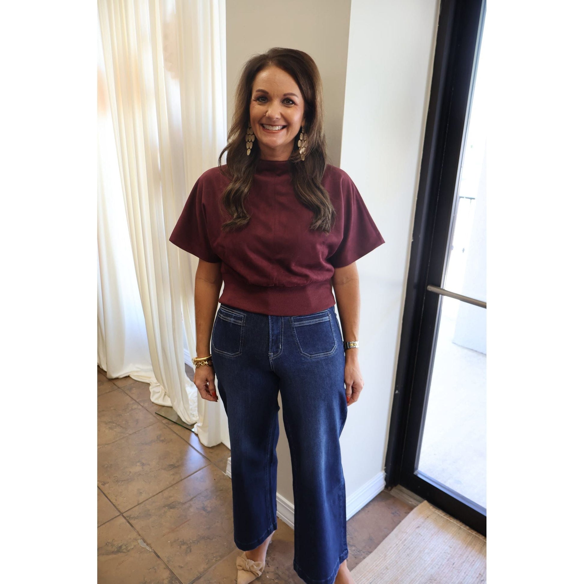 Annie Ks Boutique burgundy suede-look mock neck top with short sleeves worn with dark blue wide-leg denim jeans.