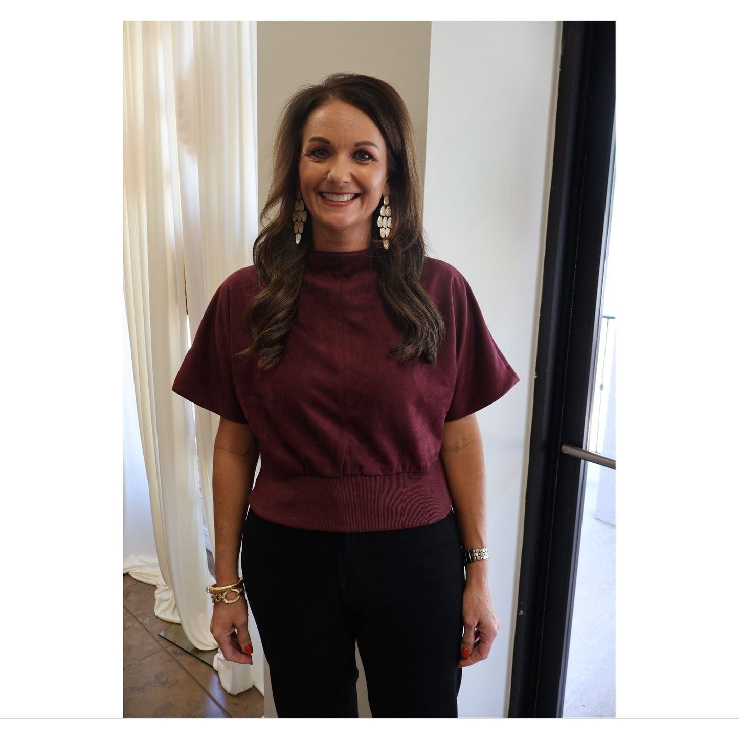 A woman wearing an Annie Ks Boutique burgundy suede-look mock neck top with short sleeves and a ribbed hem.