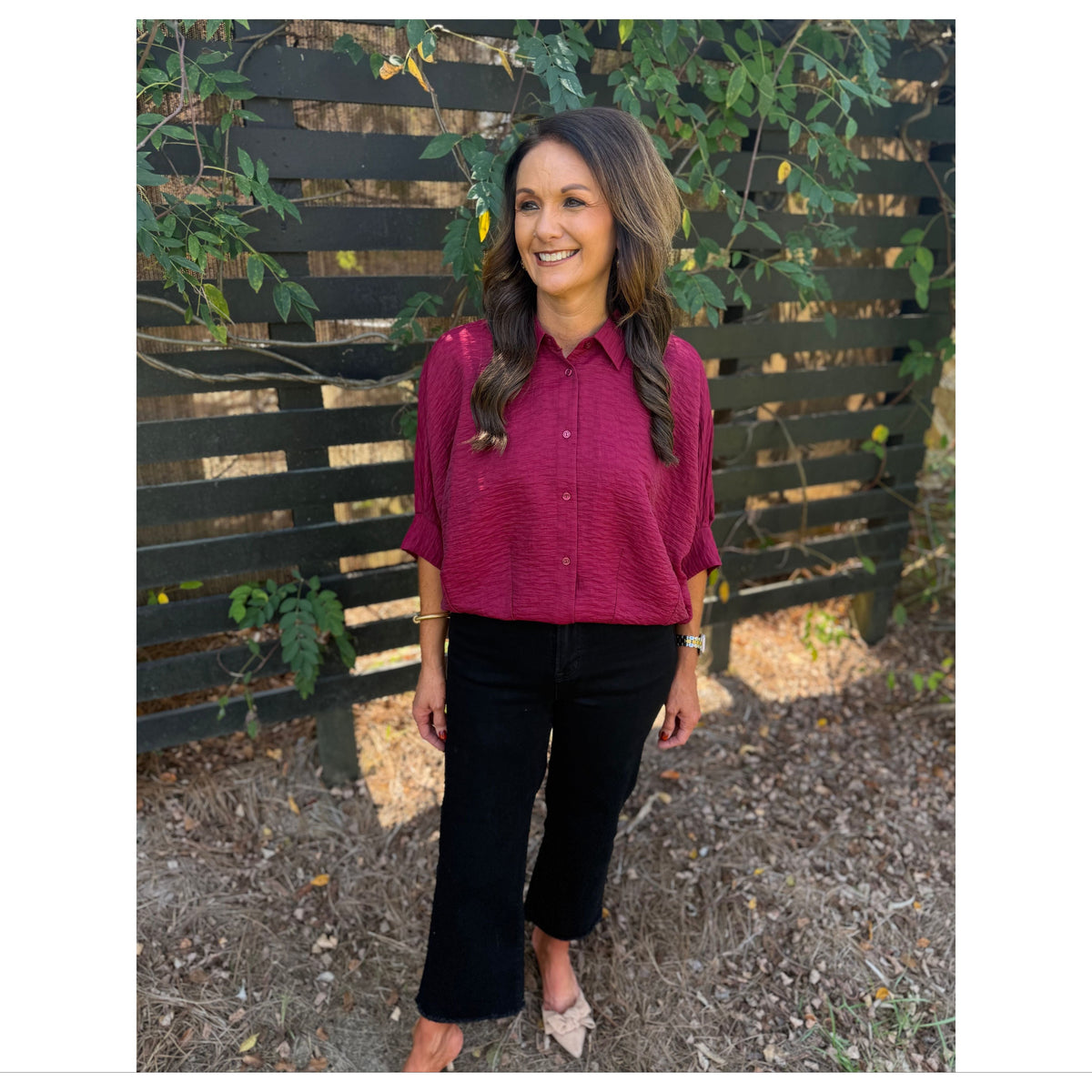 Annie Ks Boutique burgundy textured short sleeve blouse with a button-front and collar worn with black cropped pants.