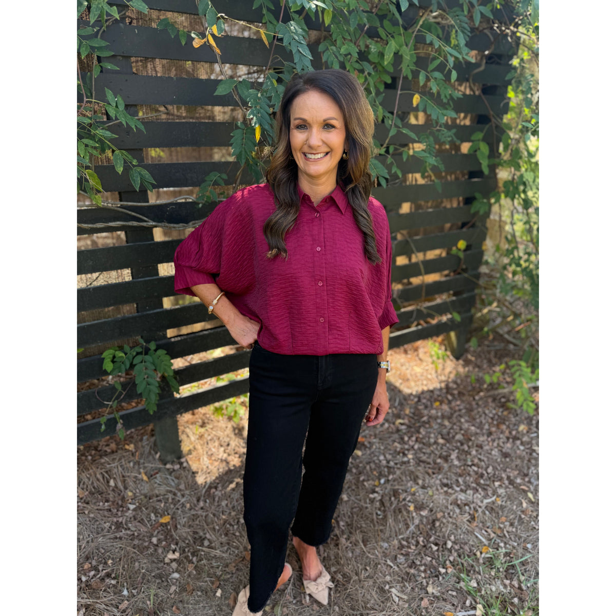 Annie Ks Boutique burgundy textured short sleeve blouse with a collar and dolman sleeves worn with black trousers.
