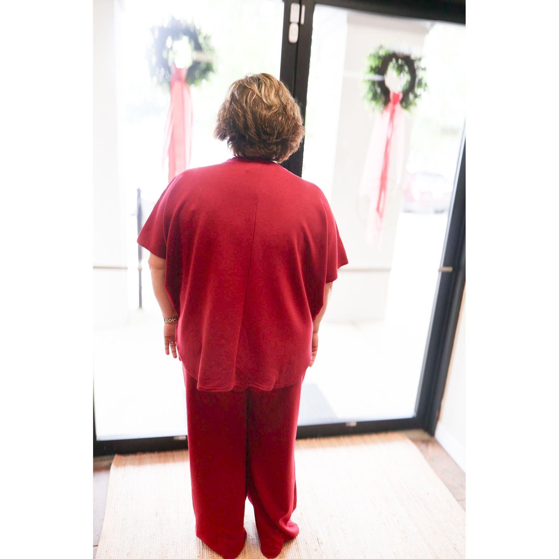 Annie Ks Boutique plus size scuba top and pants set in cabernet red with a curved hem, viewed from the back.
