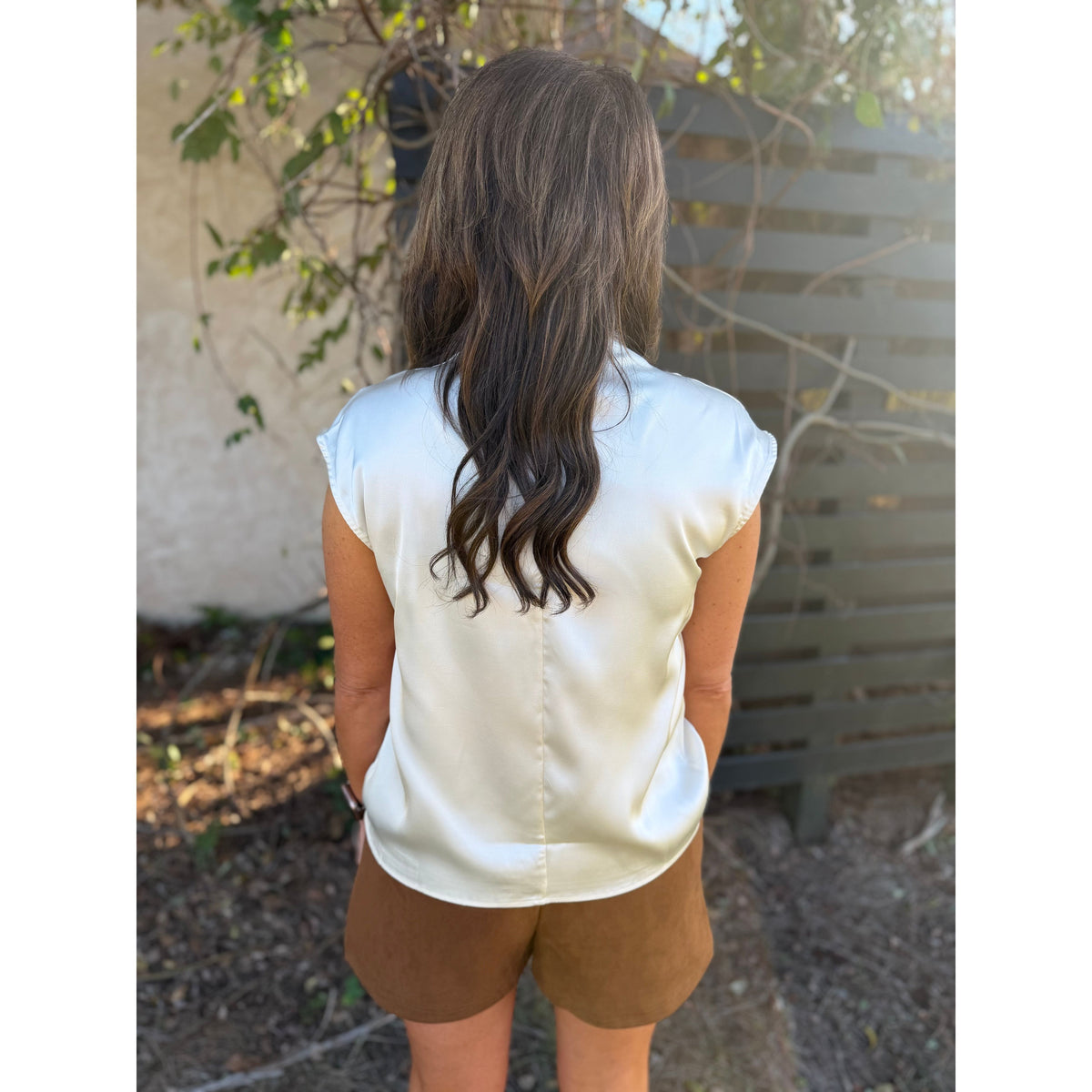 Annie Ks Boutique camel brown faux suede shorts paired with a white satin sleeveless top, viewed from behind