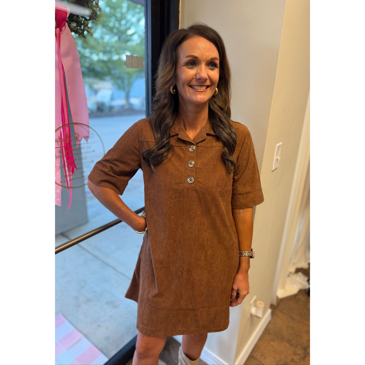 Annie Ks Boutique caramel corduroy mini dress with gold buttons and collared neckline worn by a smiling woman
