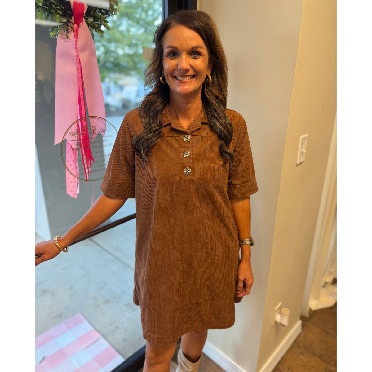 Woman wearing an Annie Ks Boutique caramel corduroy mini dress with gold buttons and a collared neckline