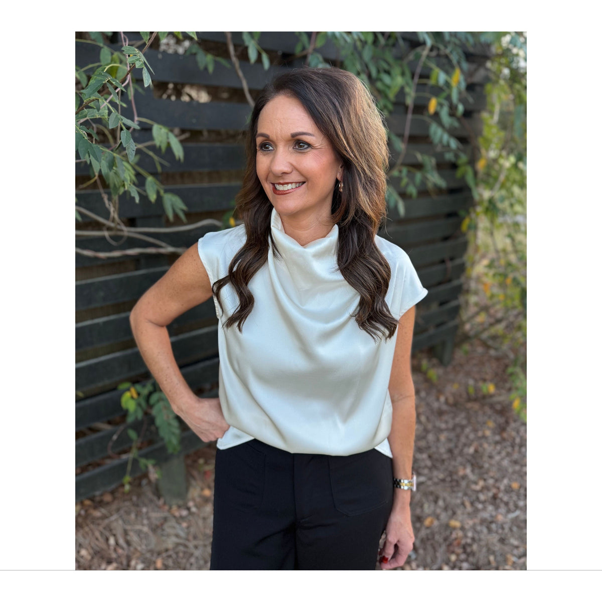 Annie Ks Boutique champagne satin sleeveless top with a draped cowl neck worn by a woman outdoors