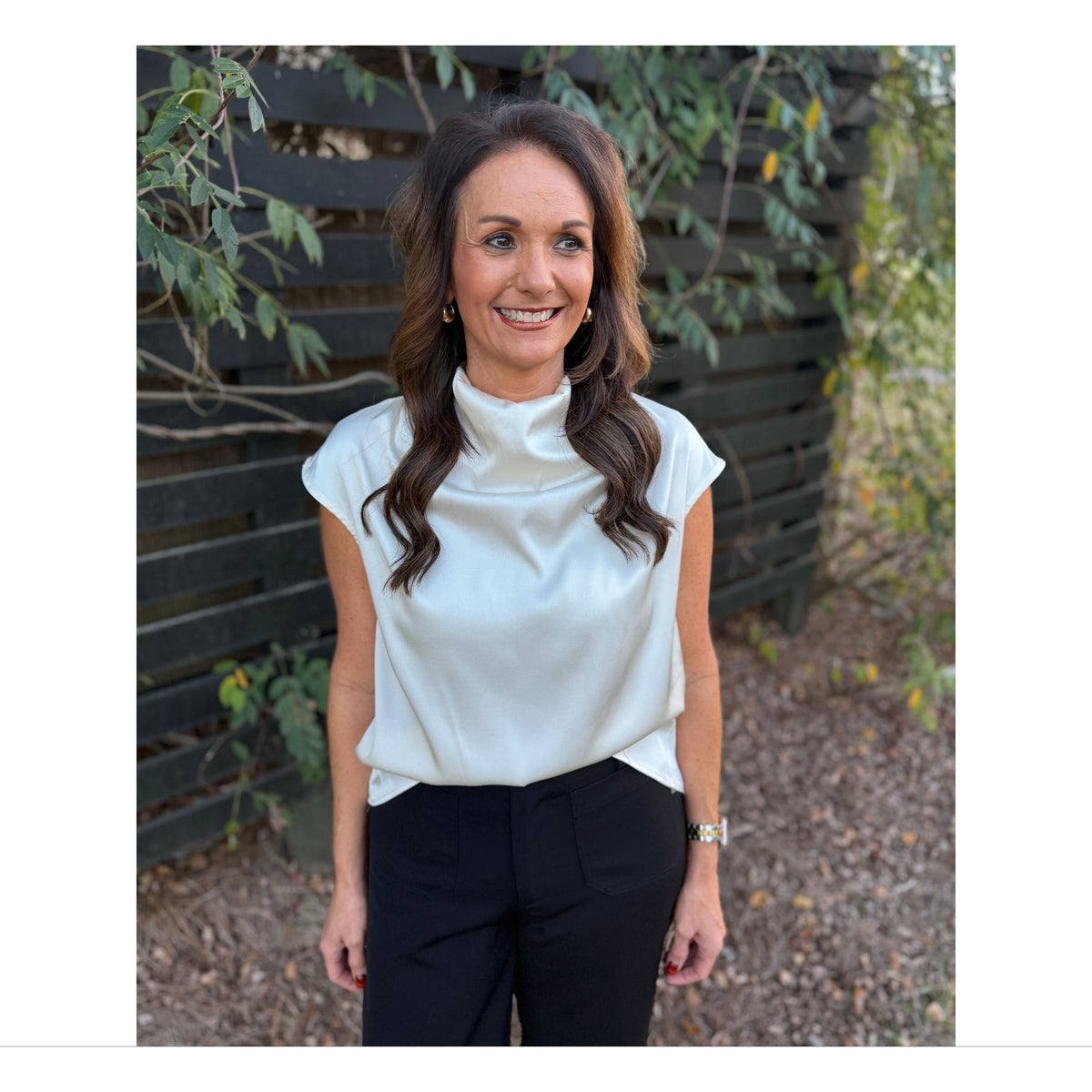 Annie Ks Boutique champagne satin sleeveless top with a draped cowl neck worn by a woman outdoors.