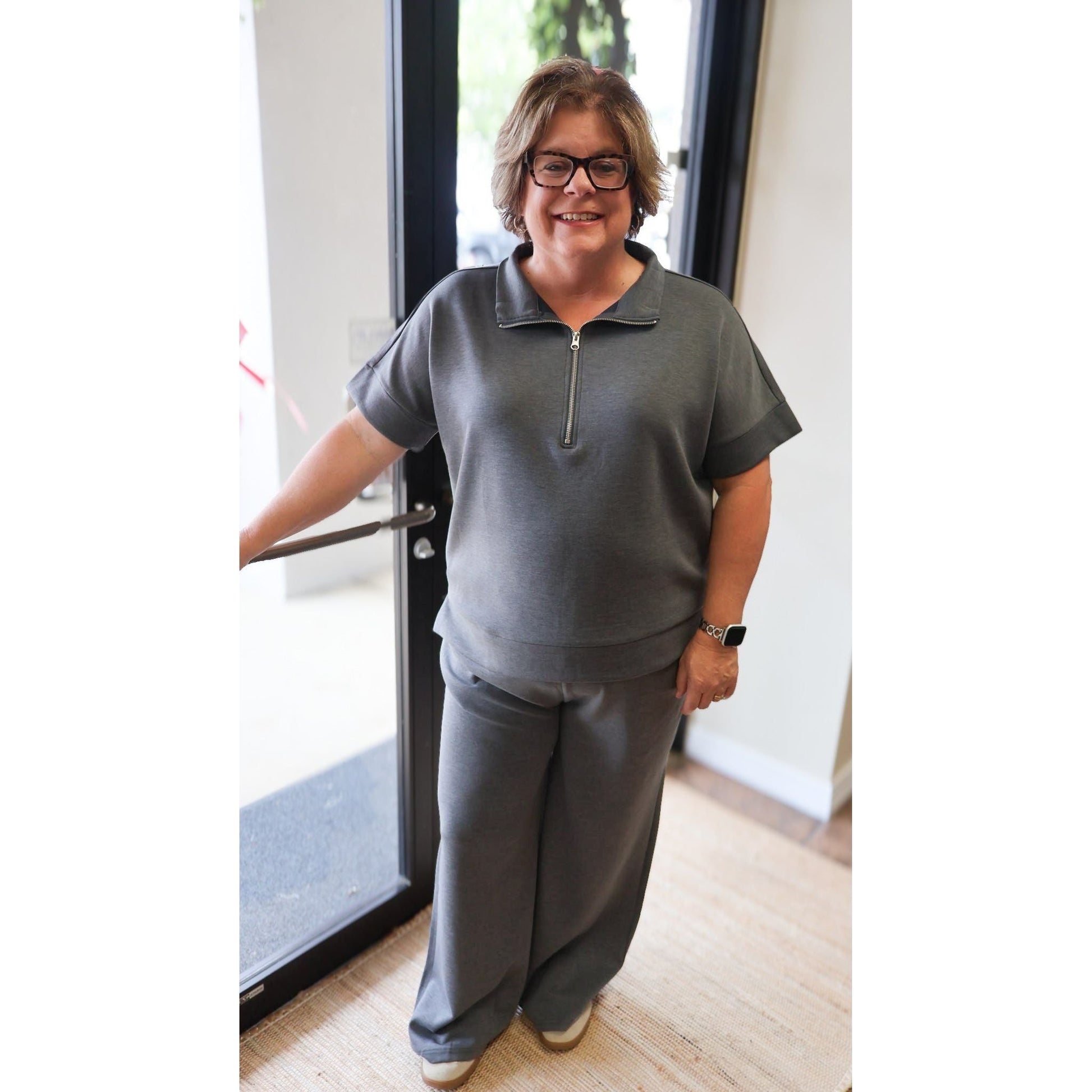 A woman wearing an Annie Ks Boutique charcoal scuba knit half-zip top and matching wide-leg pants set.
