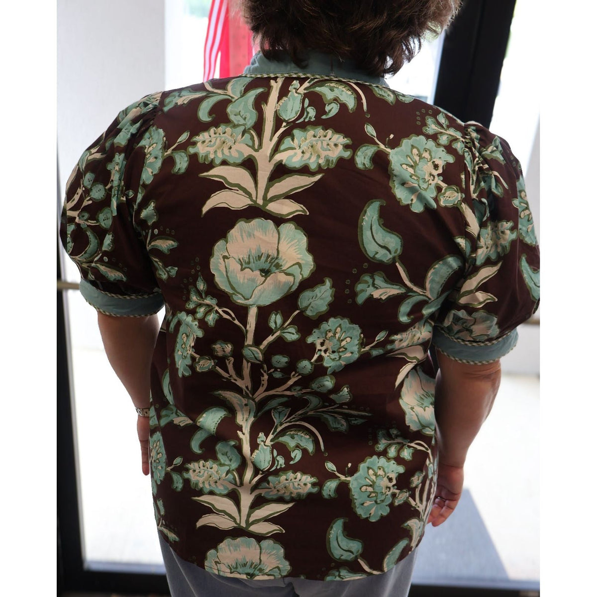 Back view of Annie Ks Boutique chocolate brown floral cotton top with short puff sleeves and contrast trim.