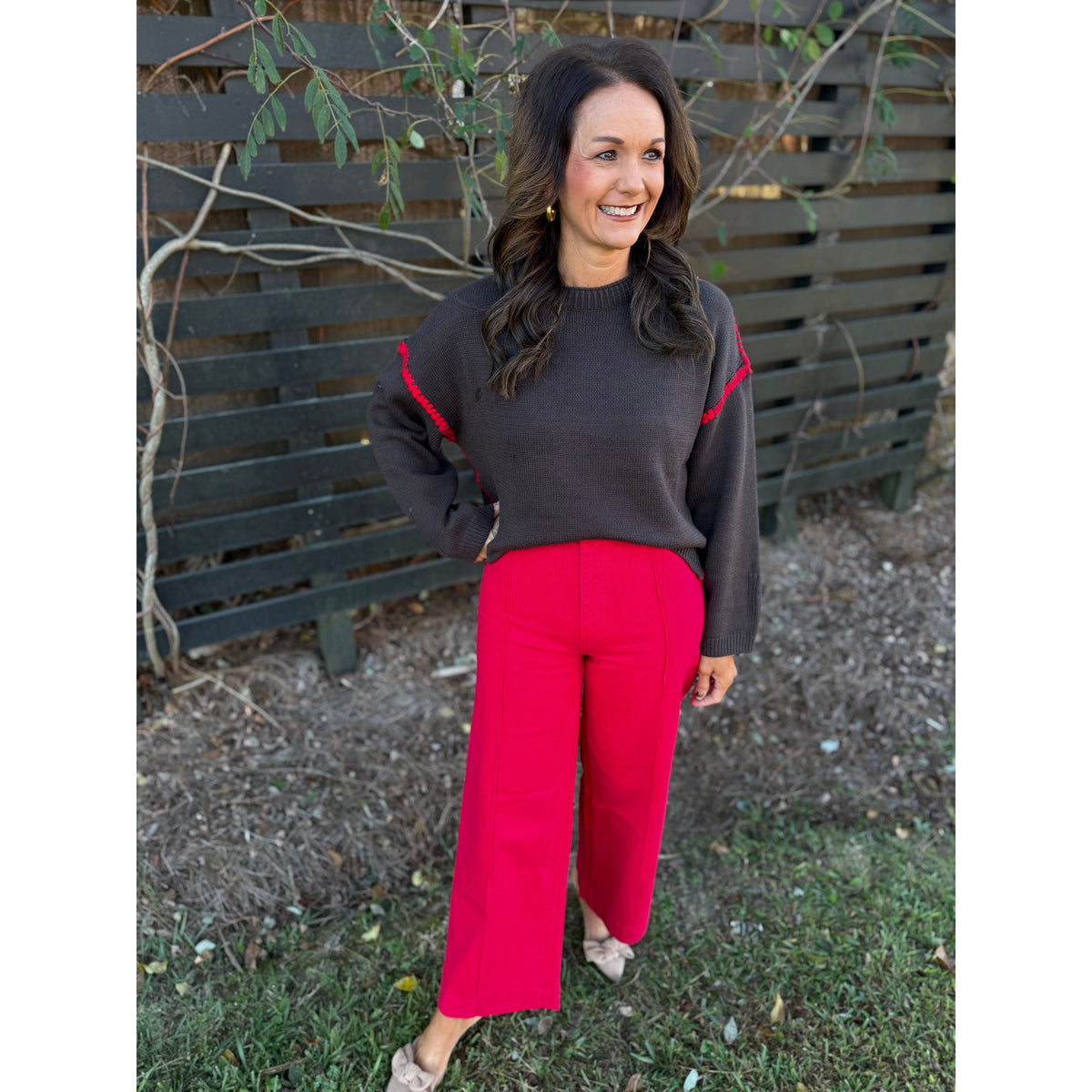 Annie Ks Boutique chocolate brown sweater with red blanket-stitch detail worn with bright red wide-leg trousers
