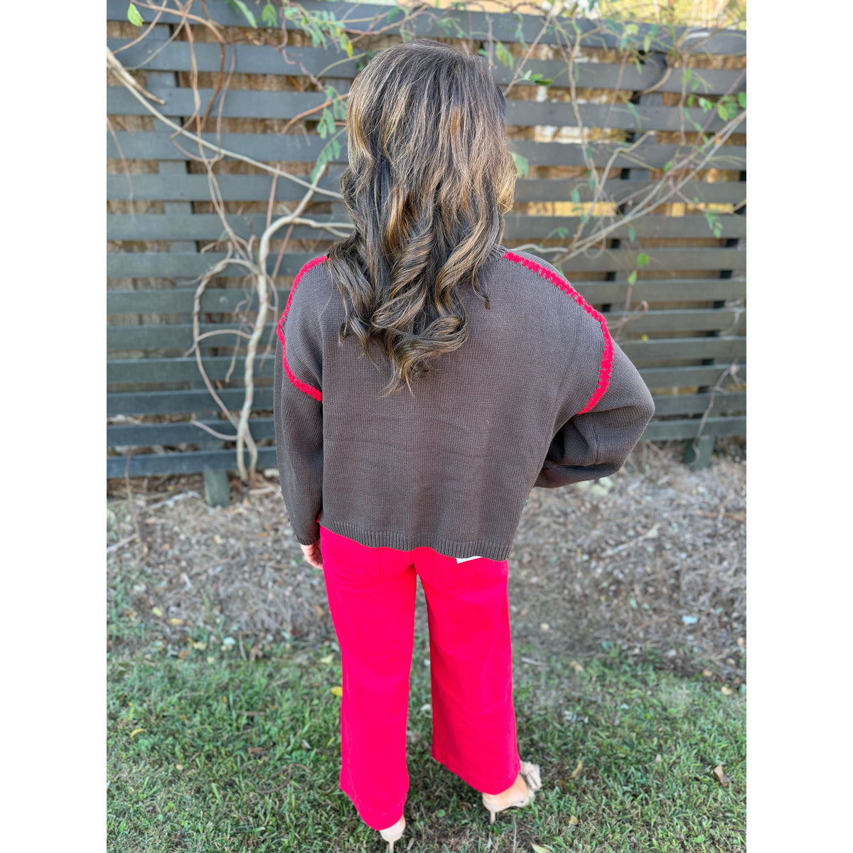 Annie Ks Boutique chocolate brown sweater with red blanket-stitch detail worn by a woman with wavy hair outdoors