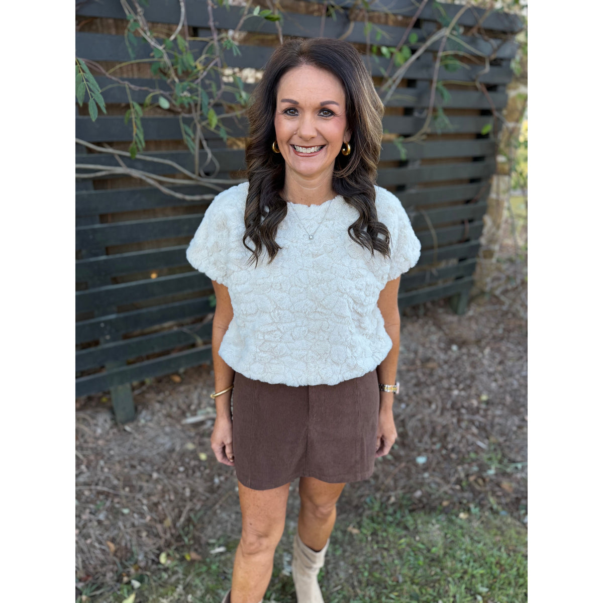 Annie Ks Boutique cream faux-fur short sleeve top worn by a woman with brown hair, paired with a brown mini skirt.