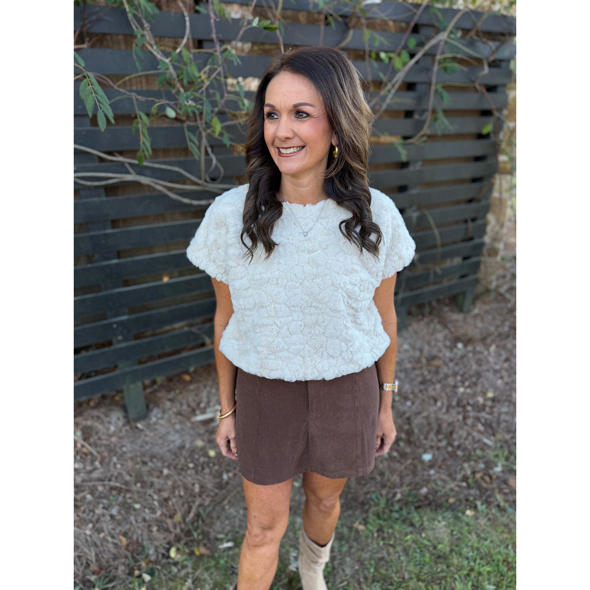 Annie Ks Boutique cream faux-fur short sleeve top worn by a woman with brown hair, paired with a brown corduroy skirt.
