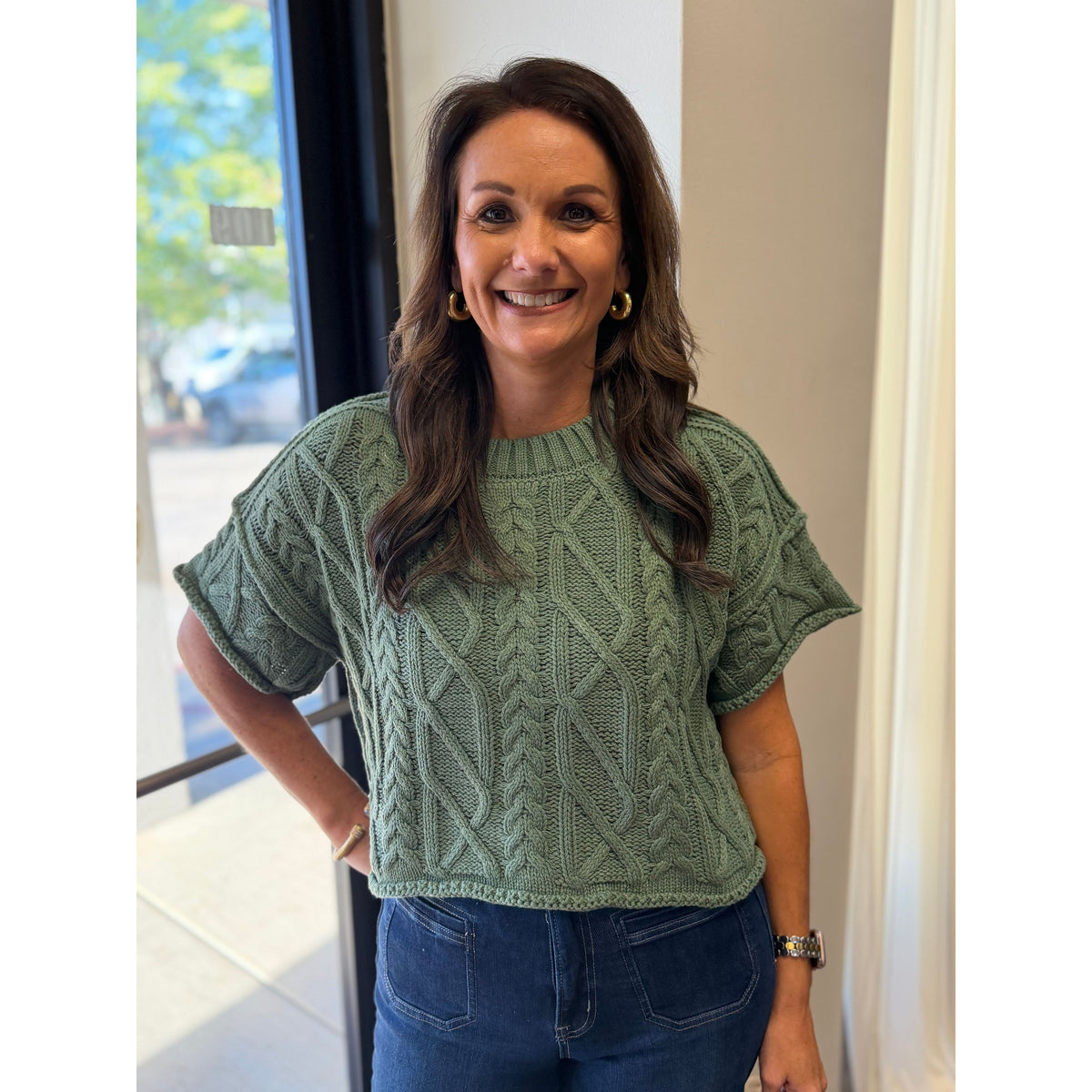 Annie Ks Boutique dusty green cropped cable knit sweater with short sleeves and a round neckline worn by a model