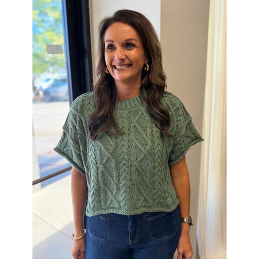 Annie Ks Boutique dusty green cropped knit sweater with cable texture and round neckline worn by a smiling woman