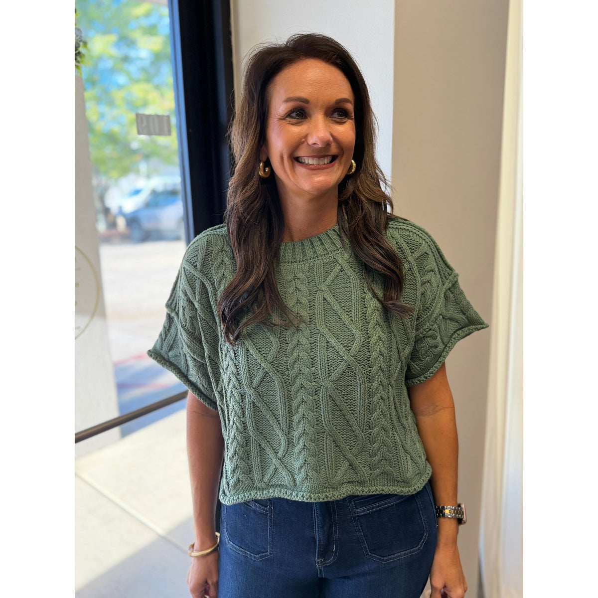 Annie Ks Boutique dusty green cropped knit sweater with cable texture and round neckline worn by a smiling woman.