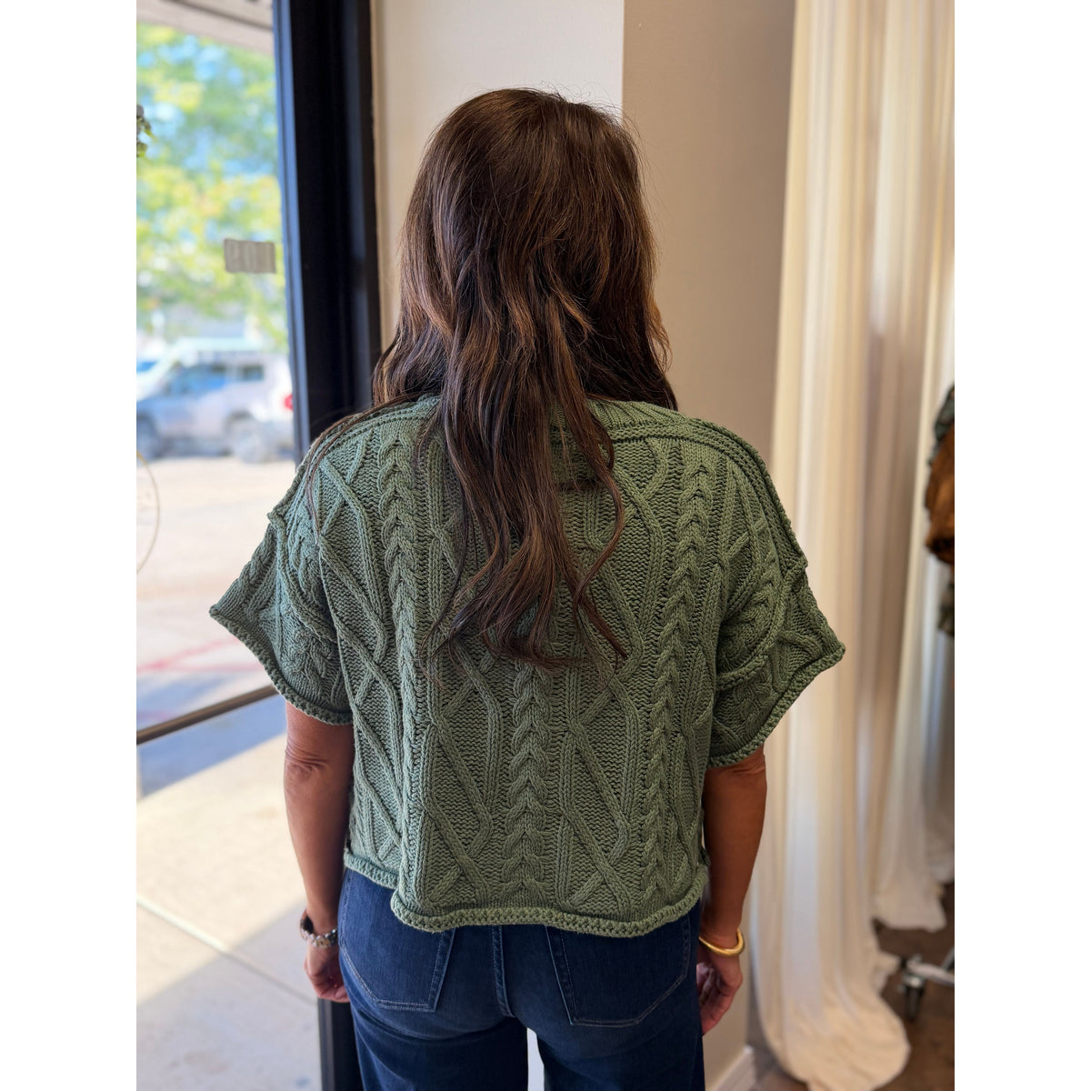 Back view of Annie Ks Boutique dusty green cropped knit sweater with cable texture and short sleeves on a model