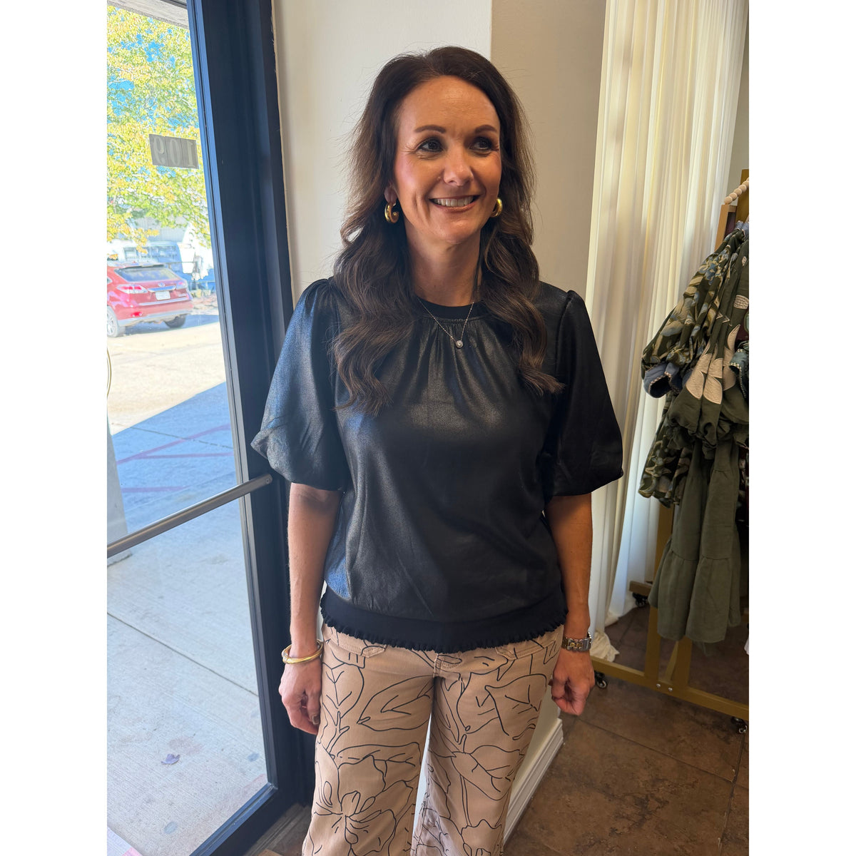 Annie Ks Boutique monochrome floral print wide leg jeans paired with a black puff sleeve top on a smiling woman