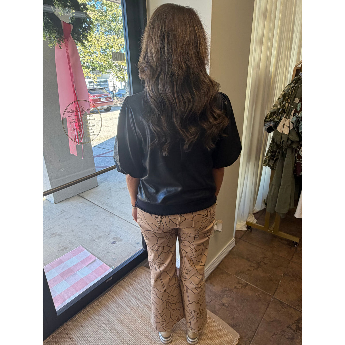 Annie Ks Boutique monochrome floral print wide-leg jeans on a model, viewed from the back in a retail store.