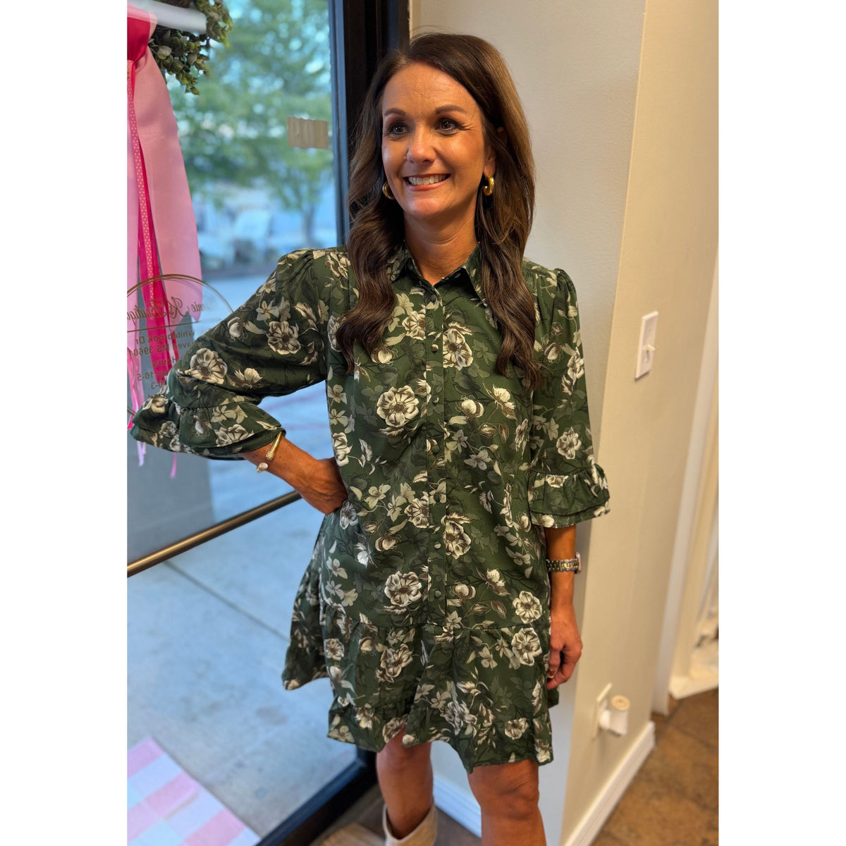 Annie Ks Boutique green floral mini dress with button-down front, ruffle sleeves, and hem worn by a smiling woman.