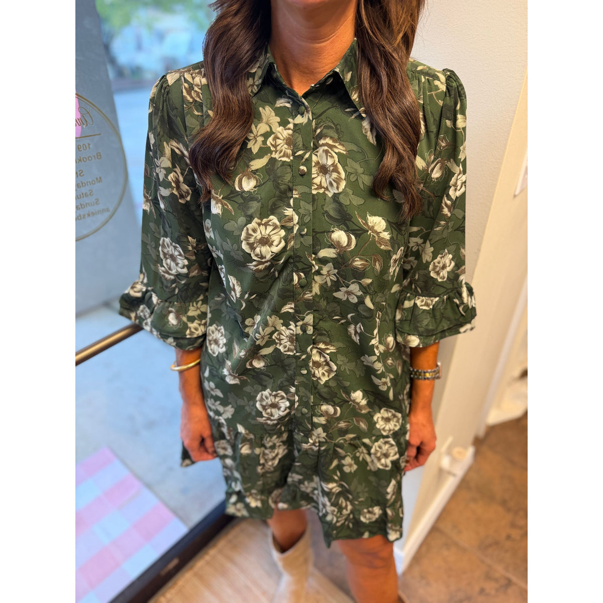 Annie Ks Boutique green floral mini dress with button-down front, collar, and ruffle-hem sleeves on a model.