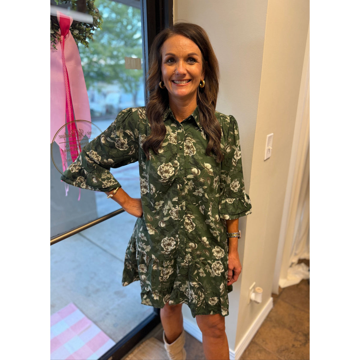 Annie Ks Boutique green floral mini dress with button-down front, ruffle sleeves, and hem worn by a smiling woman.