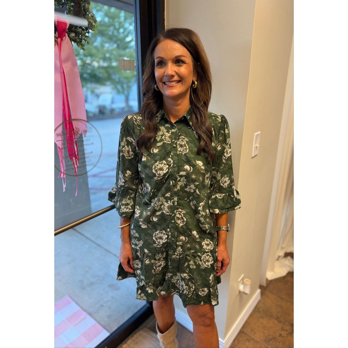 Annie Ks Boutique green floral mini dress with button-down front, ruffle sleeves, and hem worn by a smiling woman.