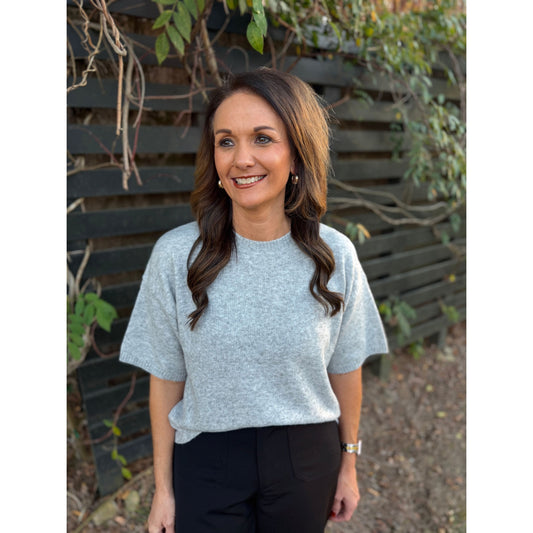 Woman wearing an Annie Ks Boutique heather grey short-sleeve boxy sweater with a crew neckline in an outdoor setting.