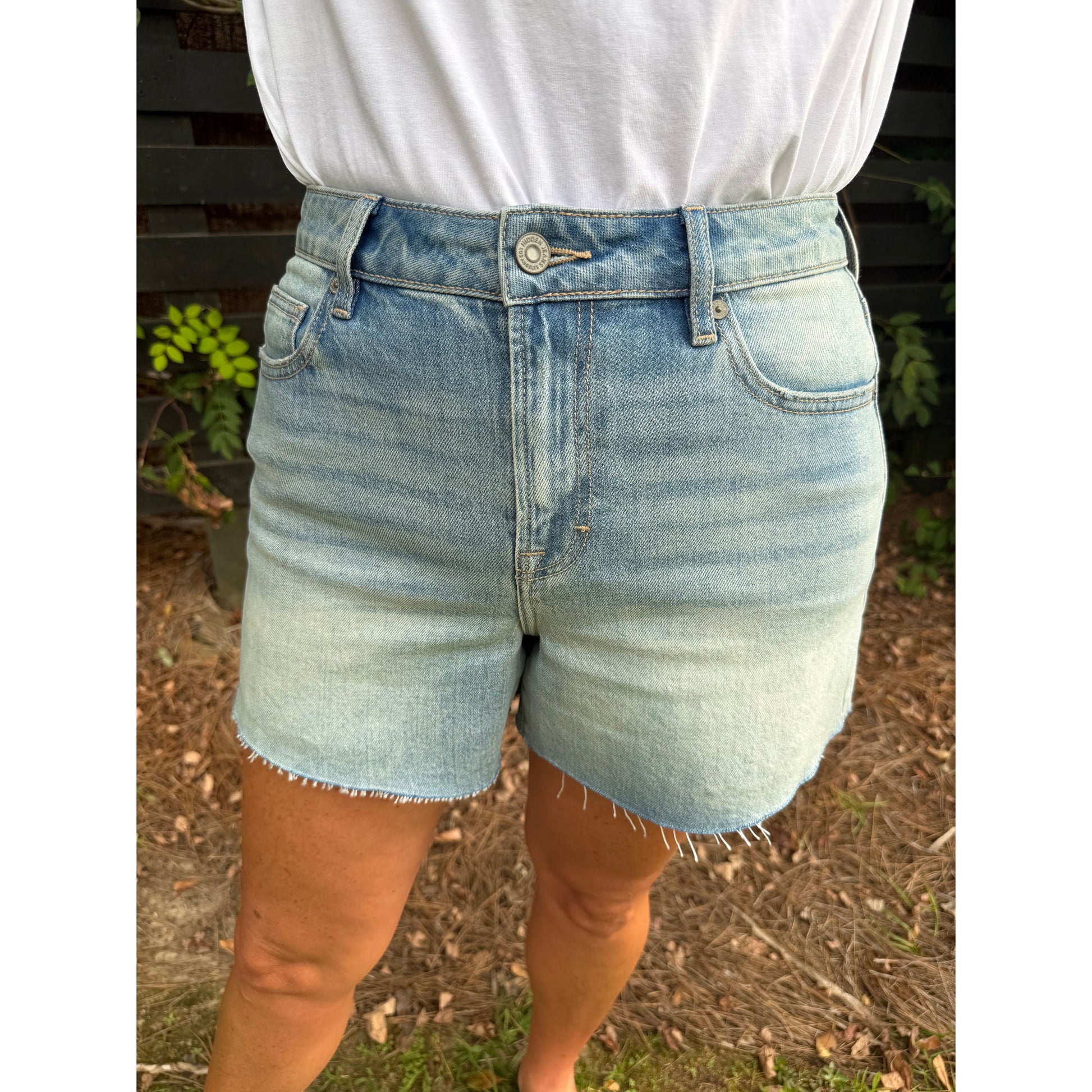 Annie Ks Boutique high-rise denim shorts in a light vintage wash with a raw hem, worn with a white t-shirt.
