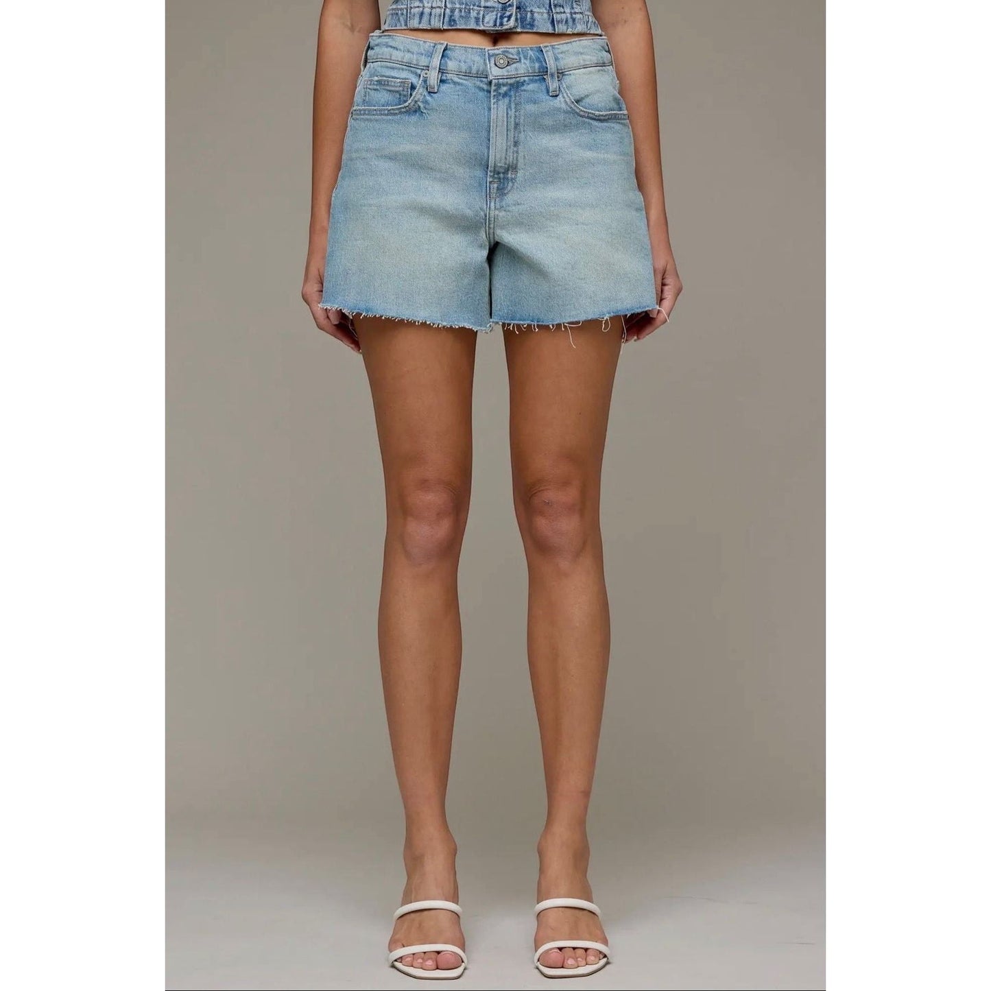 Annie Ks Boutique high-rise denim shorts in a light vintage wash with a raw hem and relaxed A-line fit on a model.
