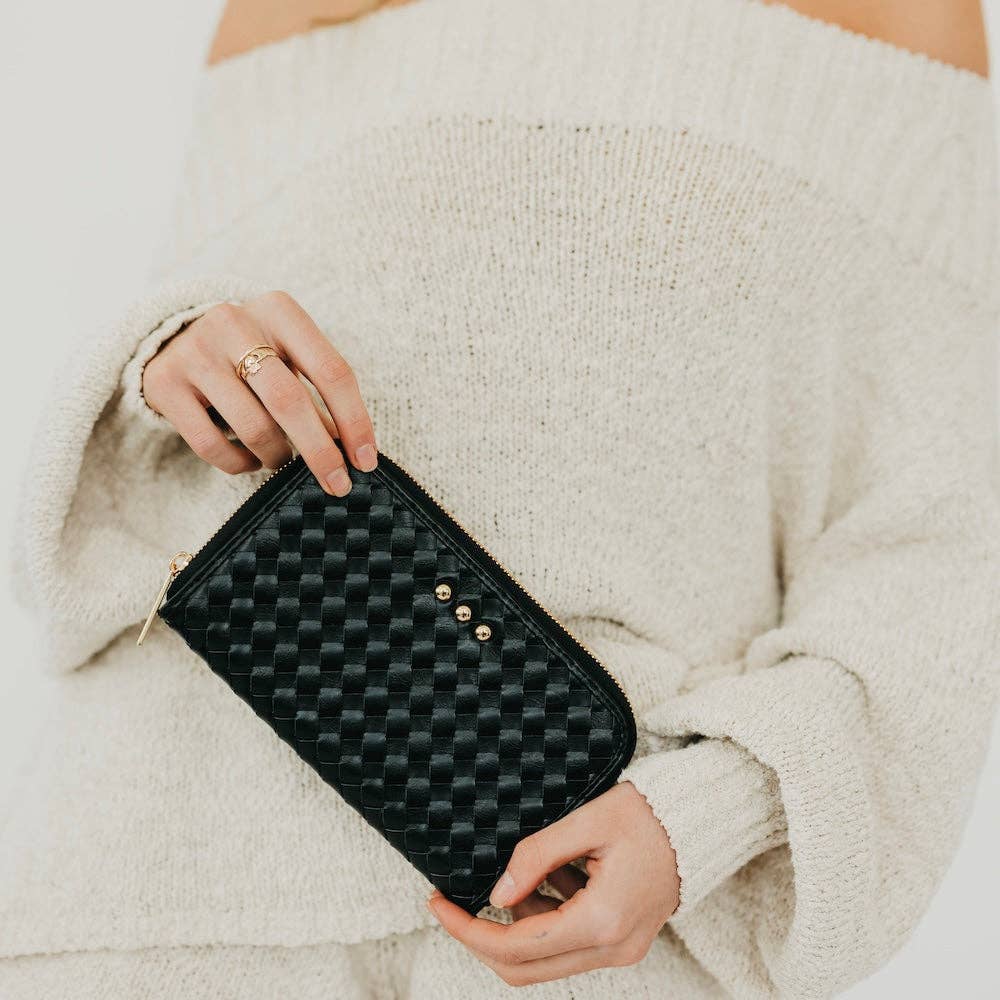 Annie Ks Boutique Lenni large black woven vegan leather zip-around wallet held by a person in a cream sweater