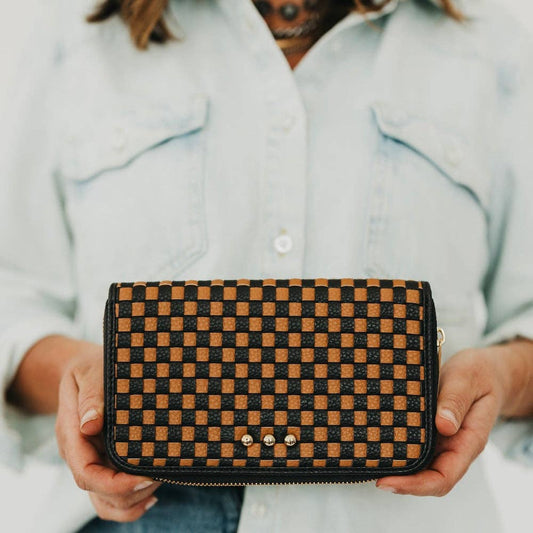 Annie Ks Boutique Lenni large zip wallet in woven checkered coffee vegan leather held by a person in a denim shirt.