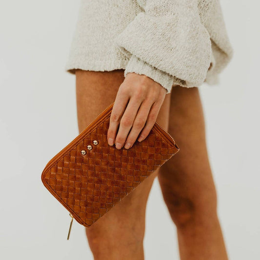 Annie Ks Boutique Lenni large brown woven vegan leather zip-around wallet held as a clutch by a woman
