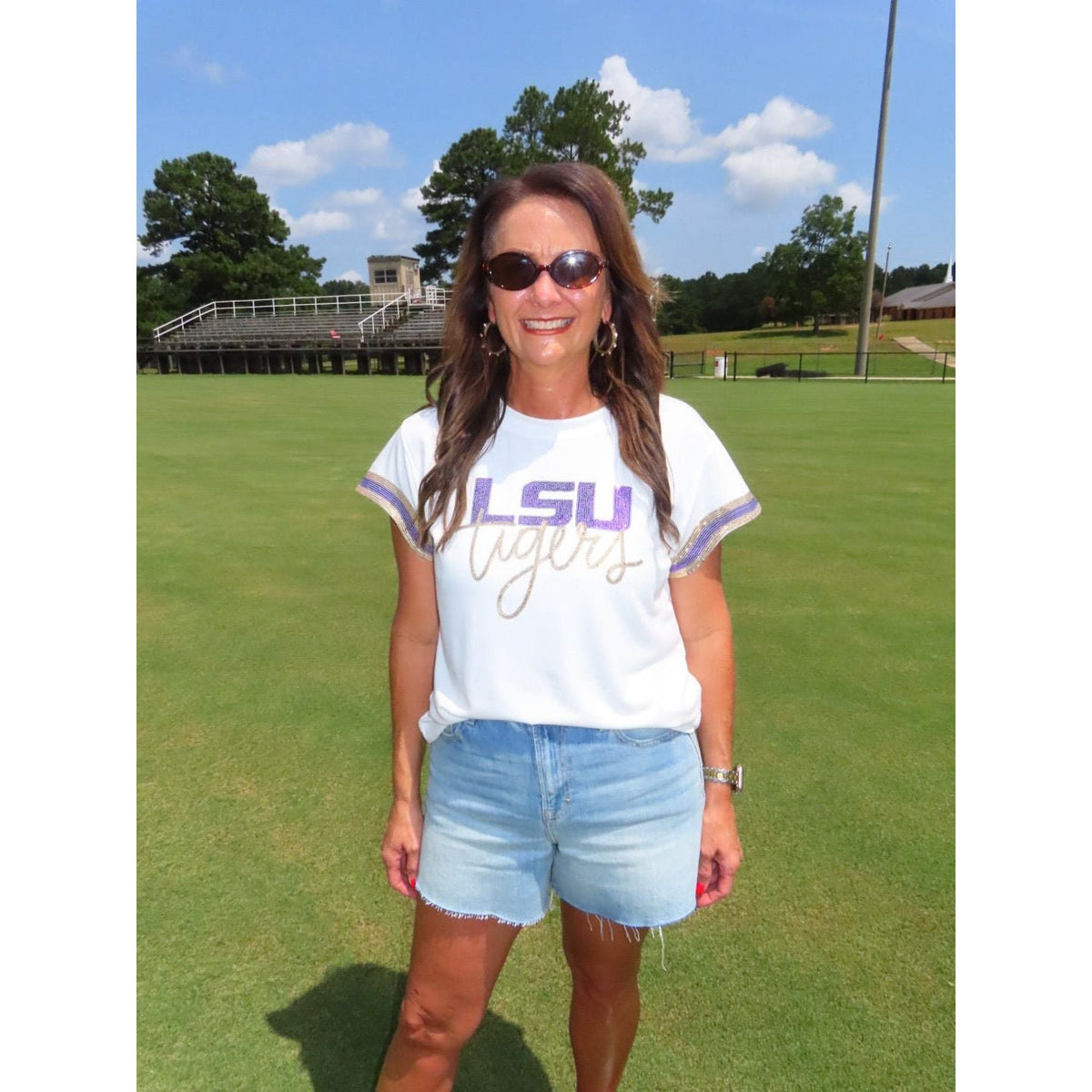 Annie Ks Boutique white Geaux Tigers sequin top with scalloped sleeves worn by a woman on a football field