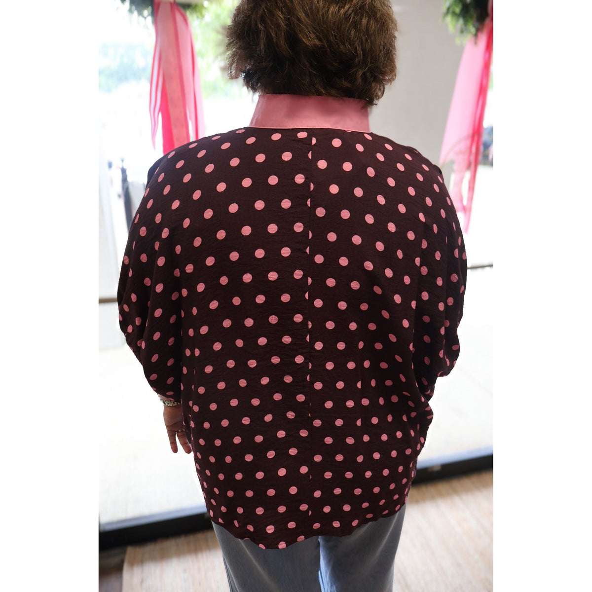 Back view of Annie Ks Boutique curvy merlot top with pink polka dots, dolman sleeves, and a contrast pink collar.